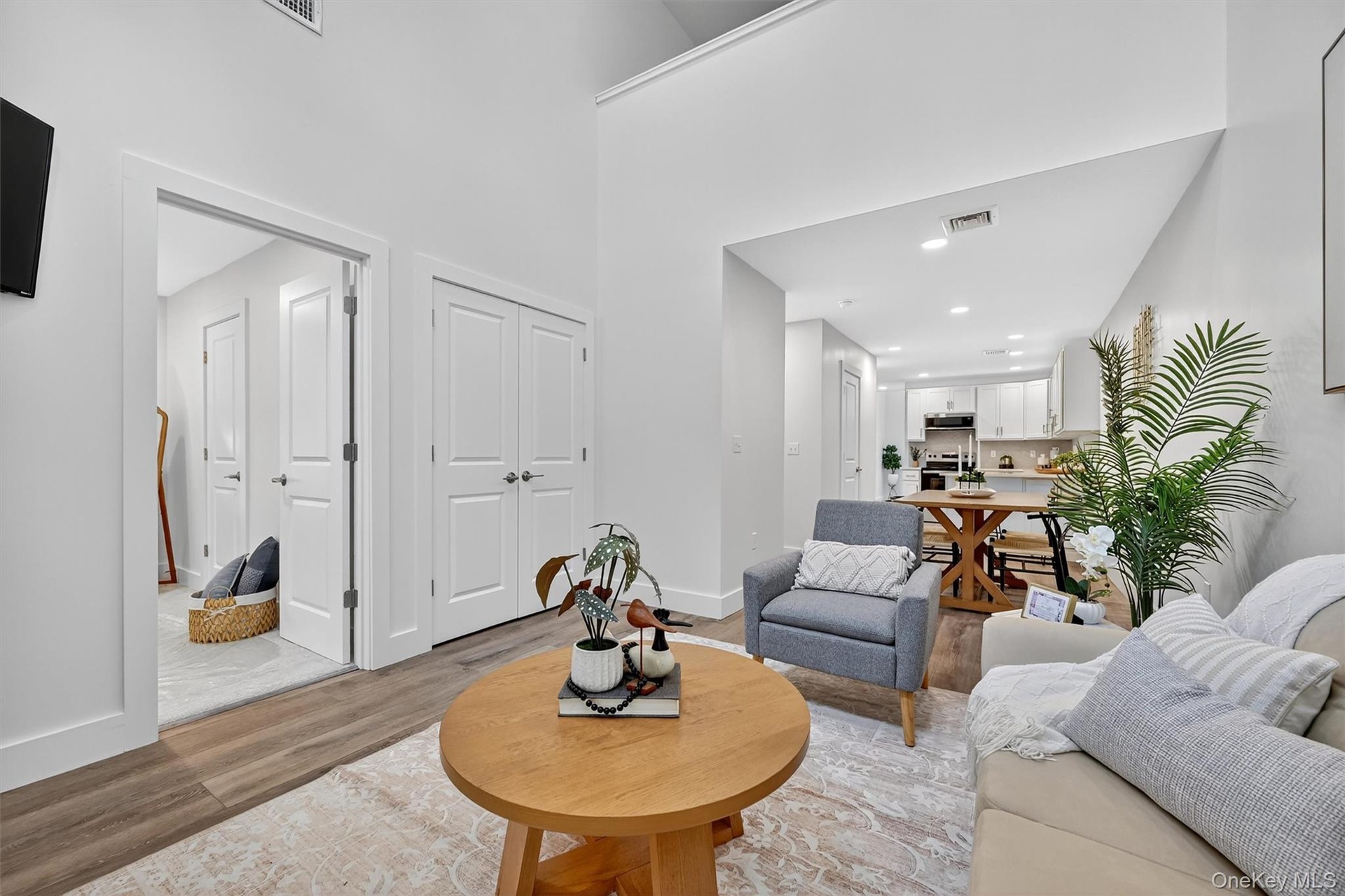 Living room with light wood-style floors, recessed lighting, and a high ceiling
