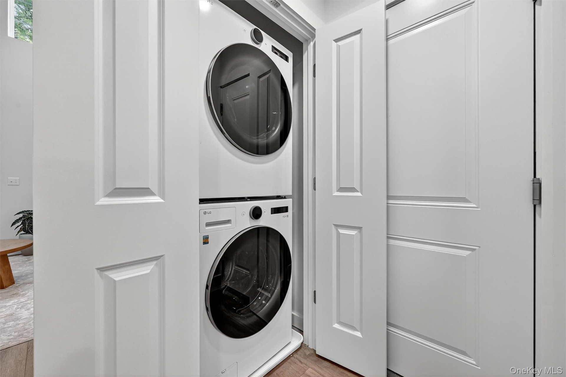 Laundry area featuring stacked washer / dryer and wood finished floors
