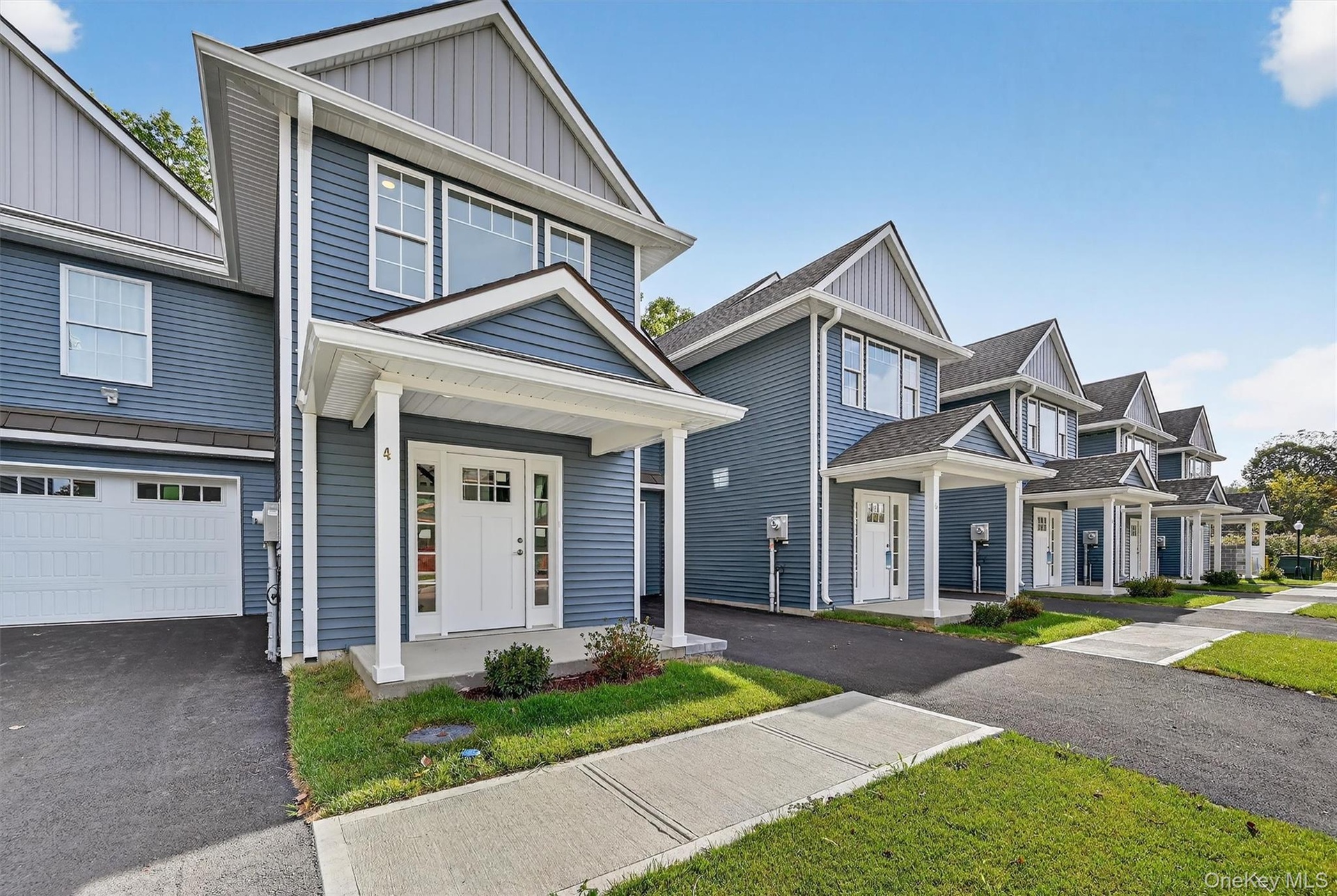 View of front of property featuring board and batten siding, covered porch, asphalt driveway, and an attached garage