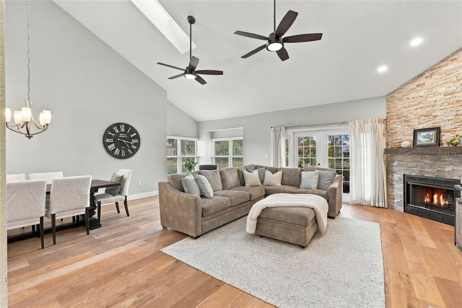 Expansive living area featuring beautiful hardwood floors, abundant natural light, and peaceful pond views.