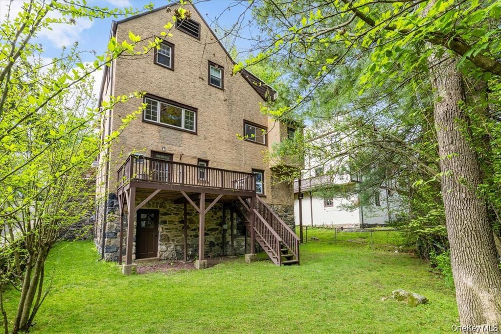 Back of house with a deck, stairs, and stone siding