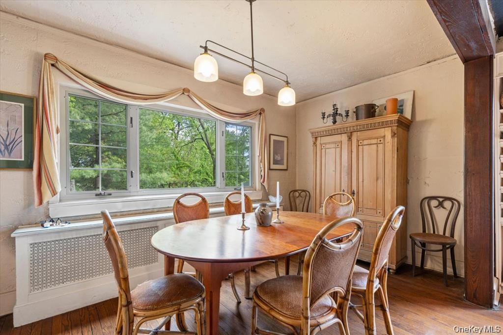 Dining area featuring light wood-type flooring, radiator, and a textured ceiling