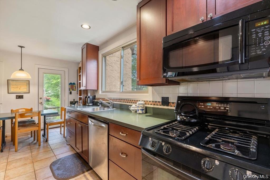 Kitchen featuring black appliances, a sink, backsplash, light tile patterned flooring, and recessed lighting