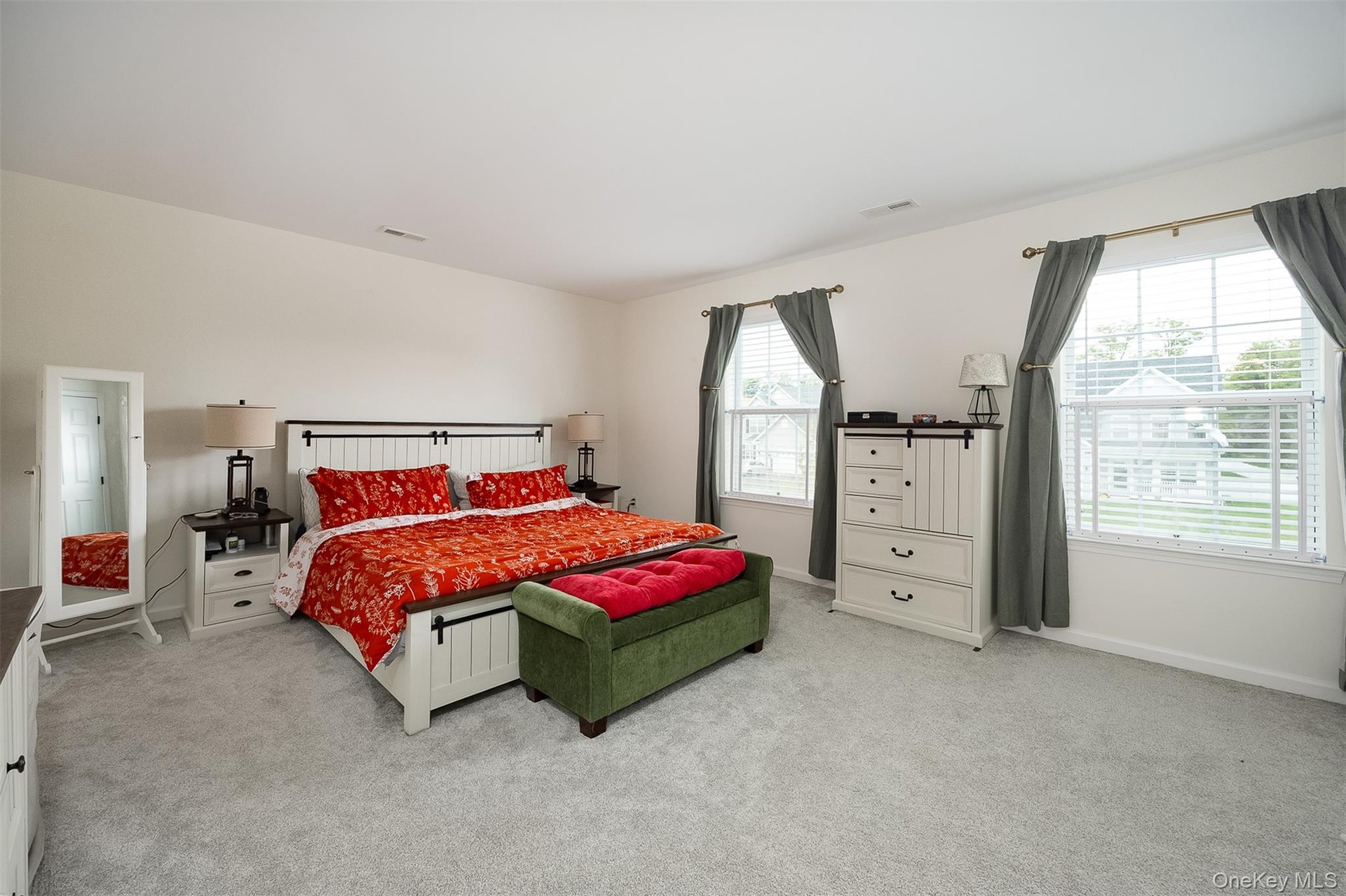 Expansive room featuring light-colored carpeting, multiple windows with blinds