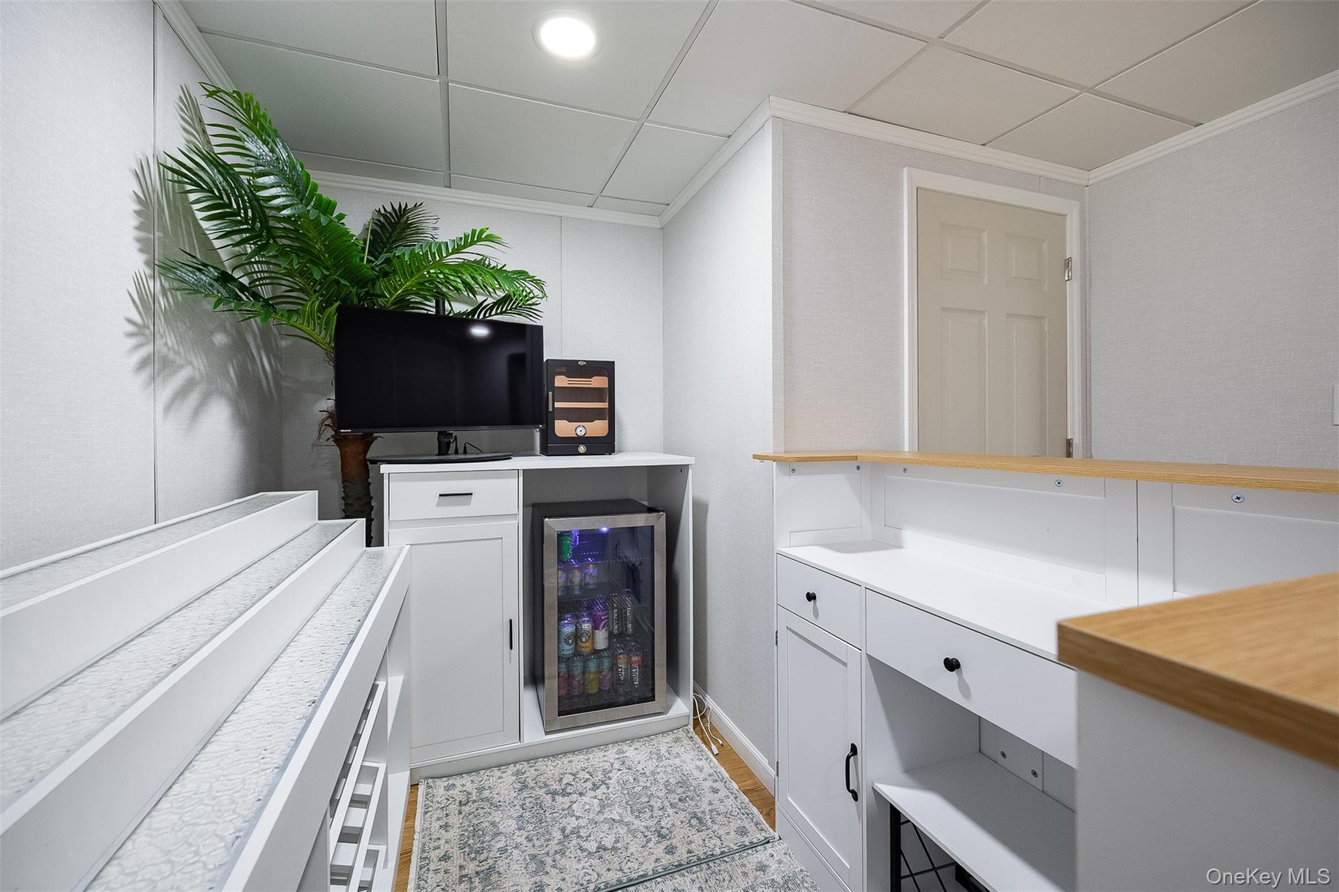 Built-in bar area featuring white cabinetry, light wood-finish countertops, and an integrated beverage refrigerator