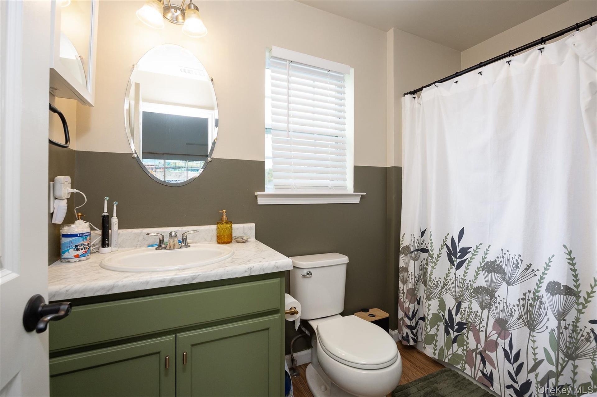 Bathroom featuring a single vanity with an integrated sink, a built-in toilet, and wood-finish flooring