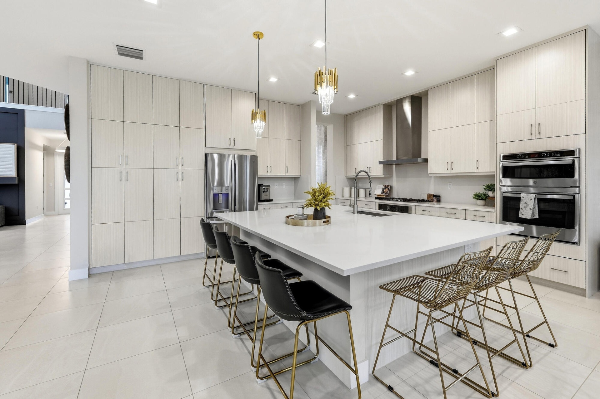 Gourmet kitchen featuring a substantial island with countertop, stainless steel appliances, extensive cabinetry, tile flooring, and integrated pendant