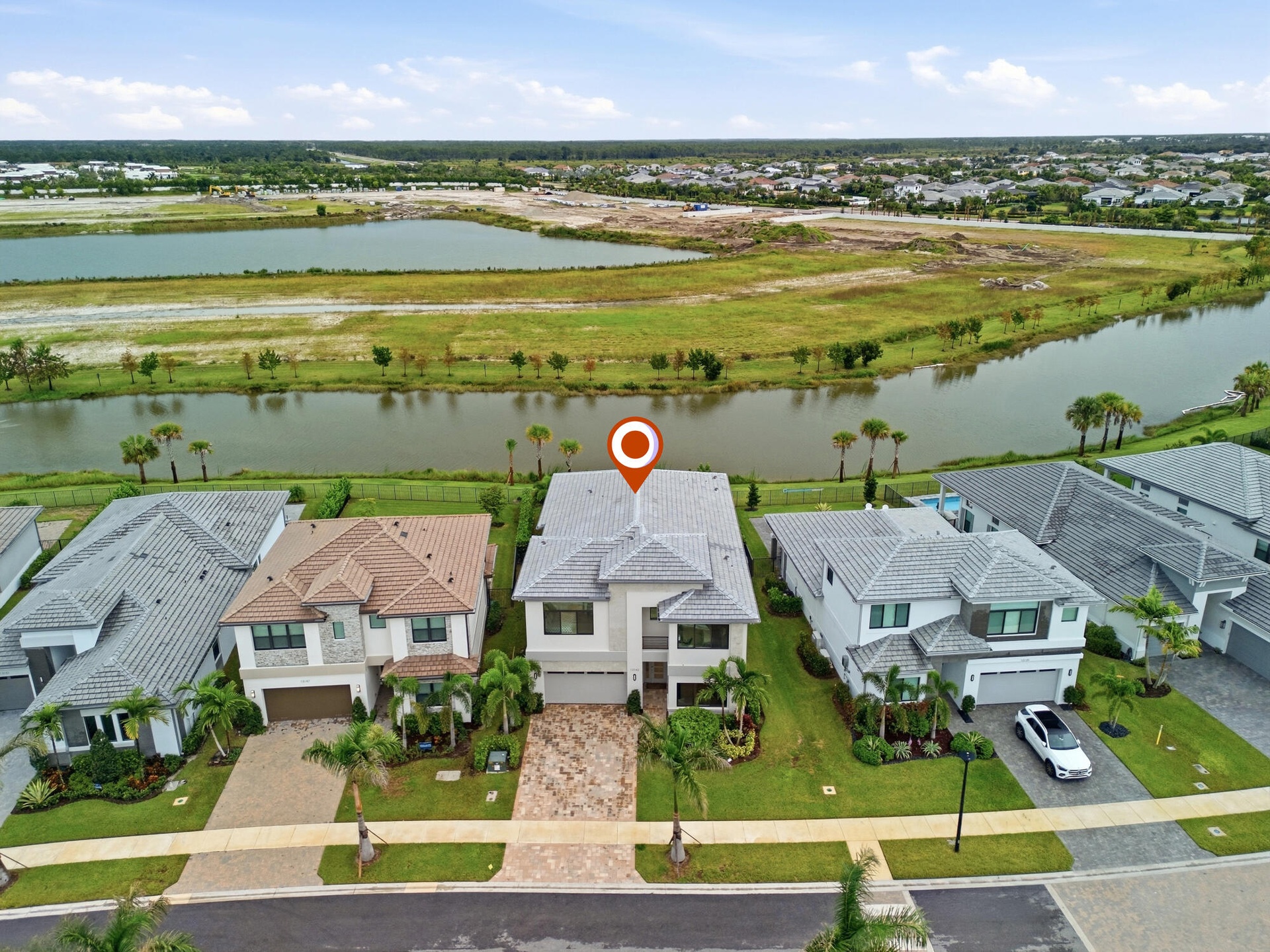 Two-story residence with a gray tile roof, light-toned exterior, paved driveway, and established landscaping
