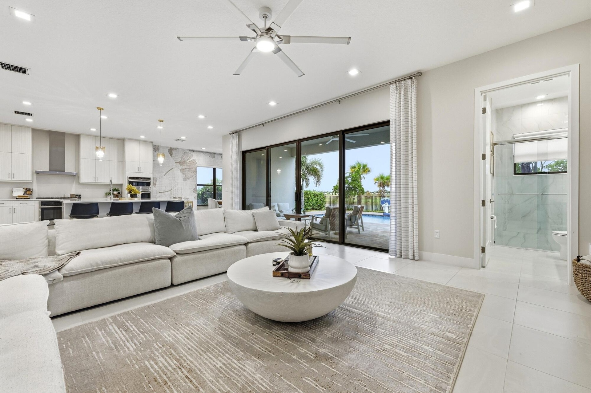 Open concept living area with recessed lighting, ceiling fan, large format tile flooring, and sliding glass doors to the exterior