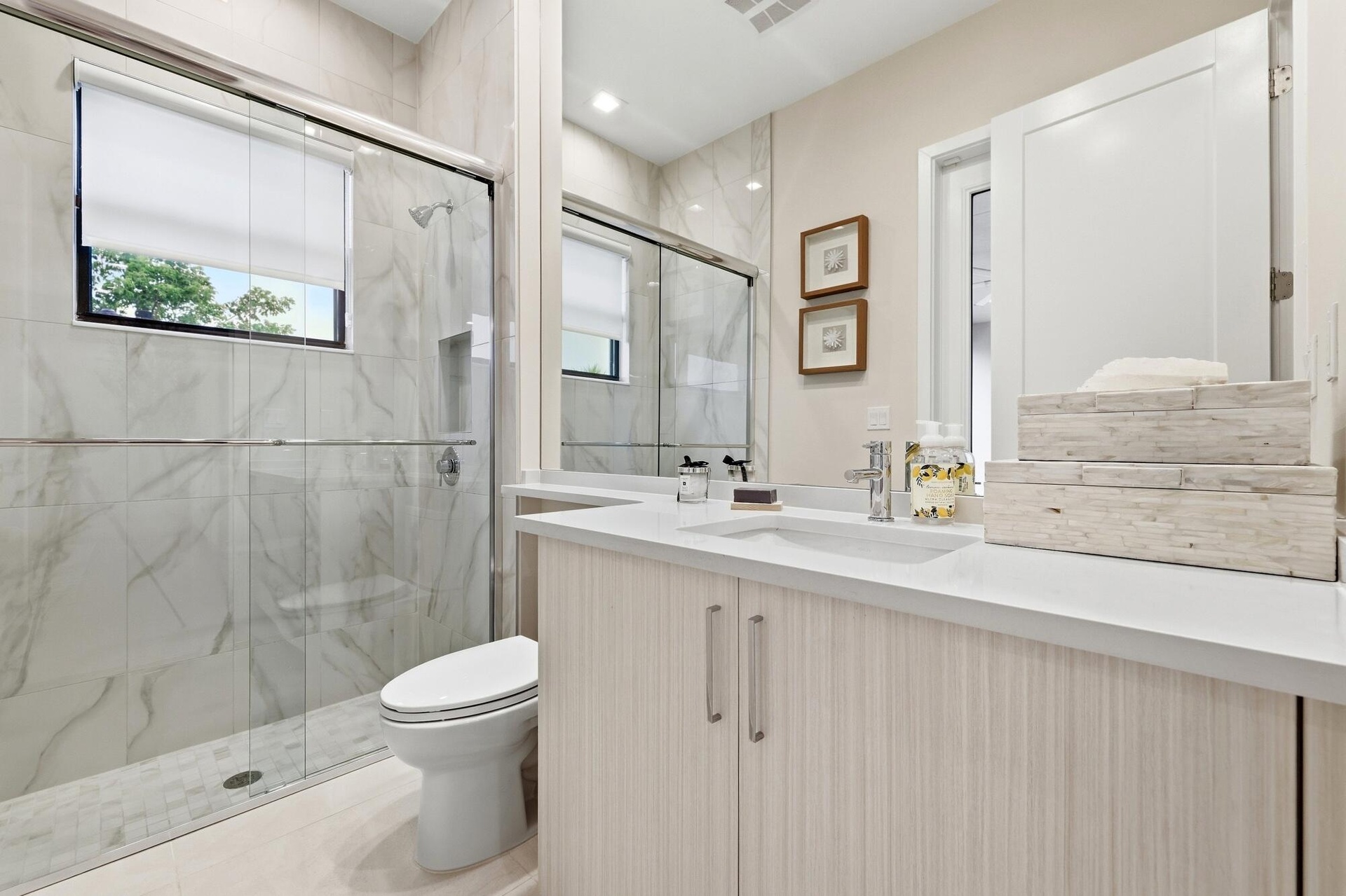 Walk-in shower with glass enclosure, integrated shower niche, and large format wall tiling