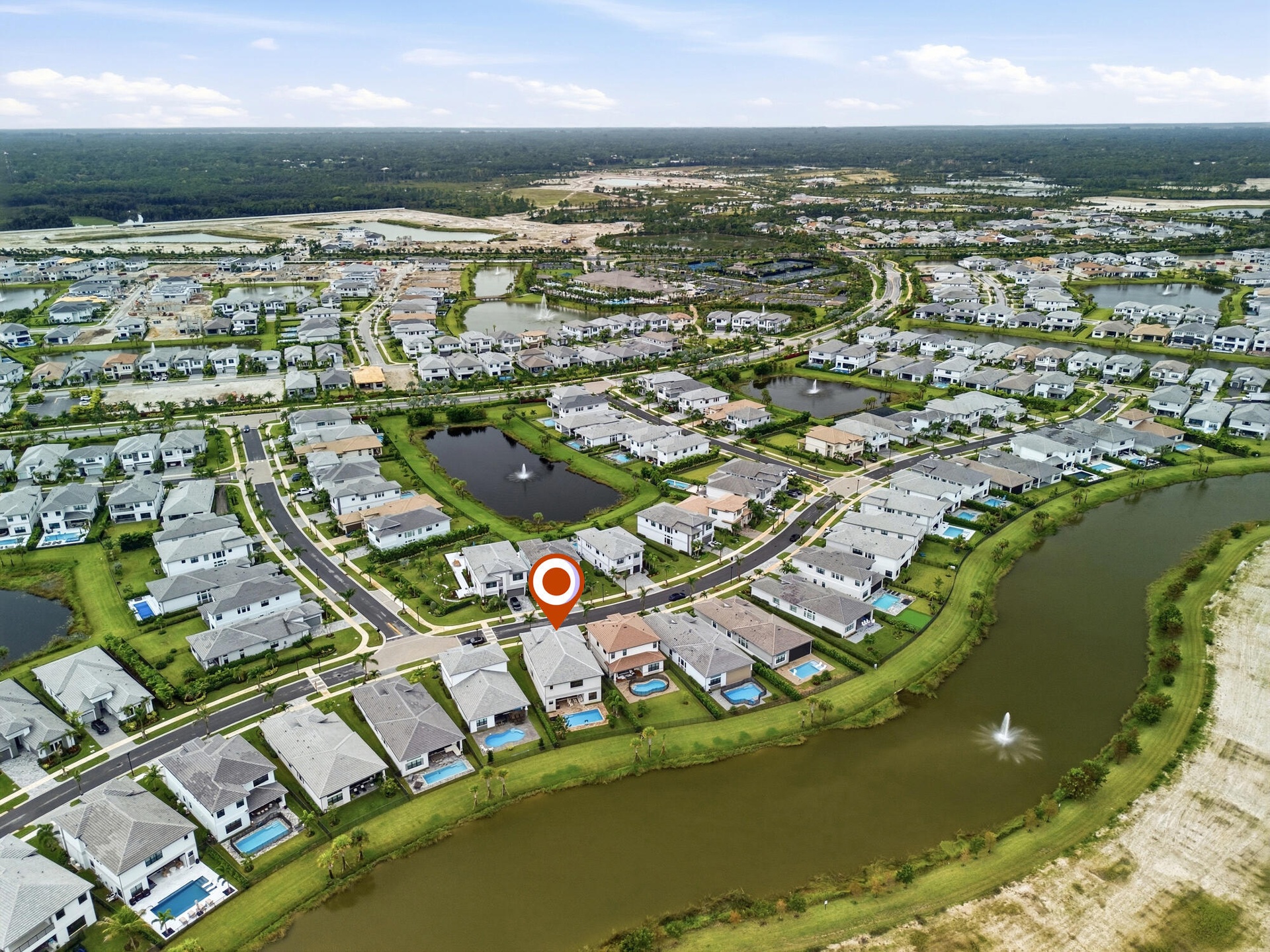 Residential community featuring a curved street pattern, multiple ponds with fountains, and an expansive surrounding greenbelt