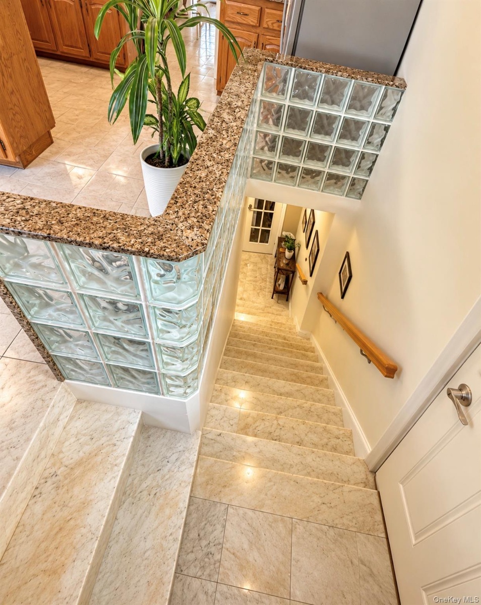 Staircase featuring light-toned tiled steps and a wood handrail