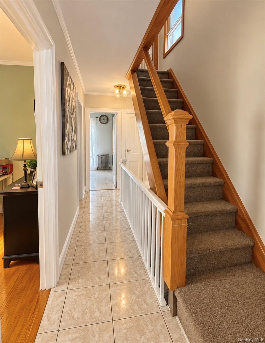 Tiled flooring, staircase with carpeted treads, wood-finish handrail, and white balusters
