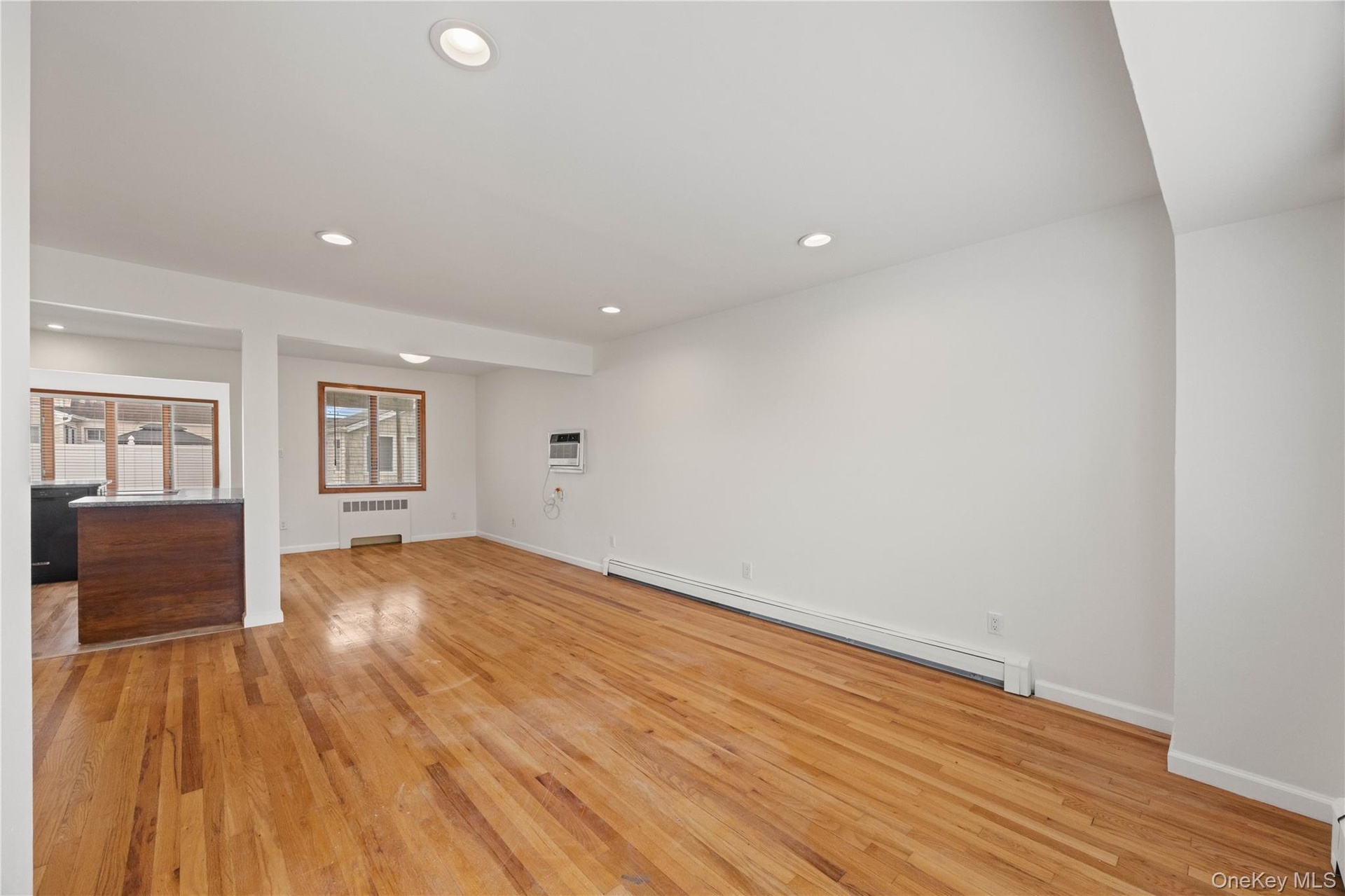 Recessed ceiling lighting, wood-finish flooring, and a built-in breakfast bar with a dark countertop