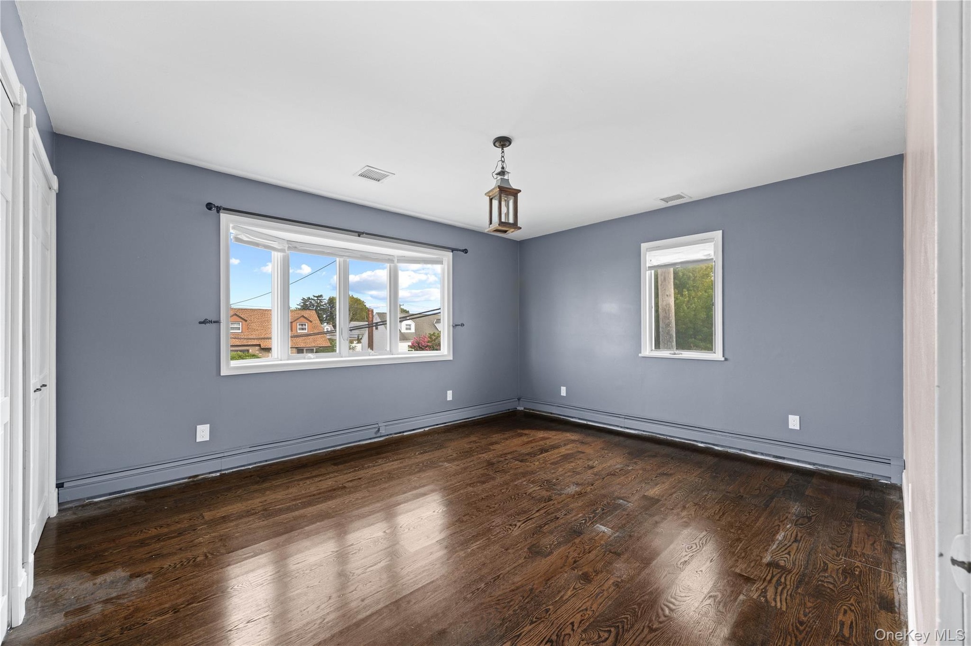 Dark wood-finish flooring with a prominent bay window