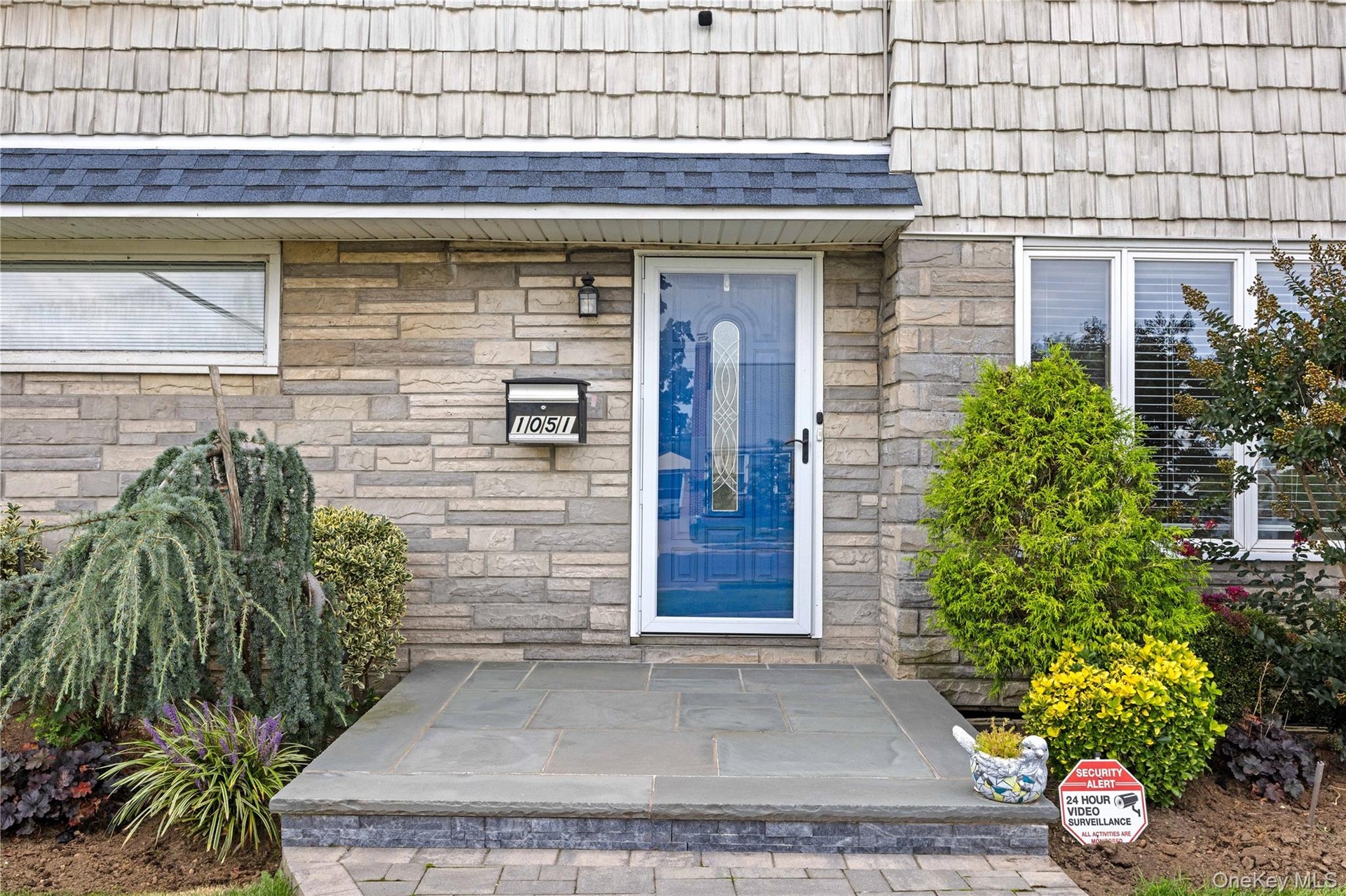 Stone veneer facade with cedar shake siding, natural stone porch, and a decorative glass storm door
