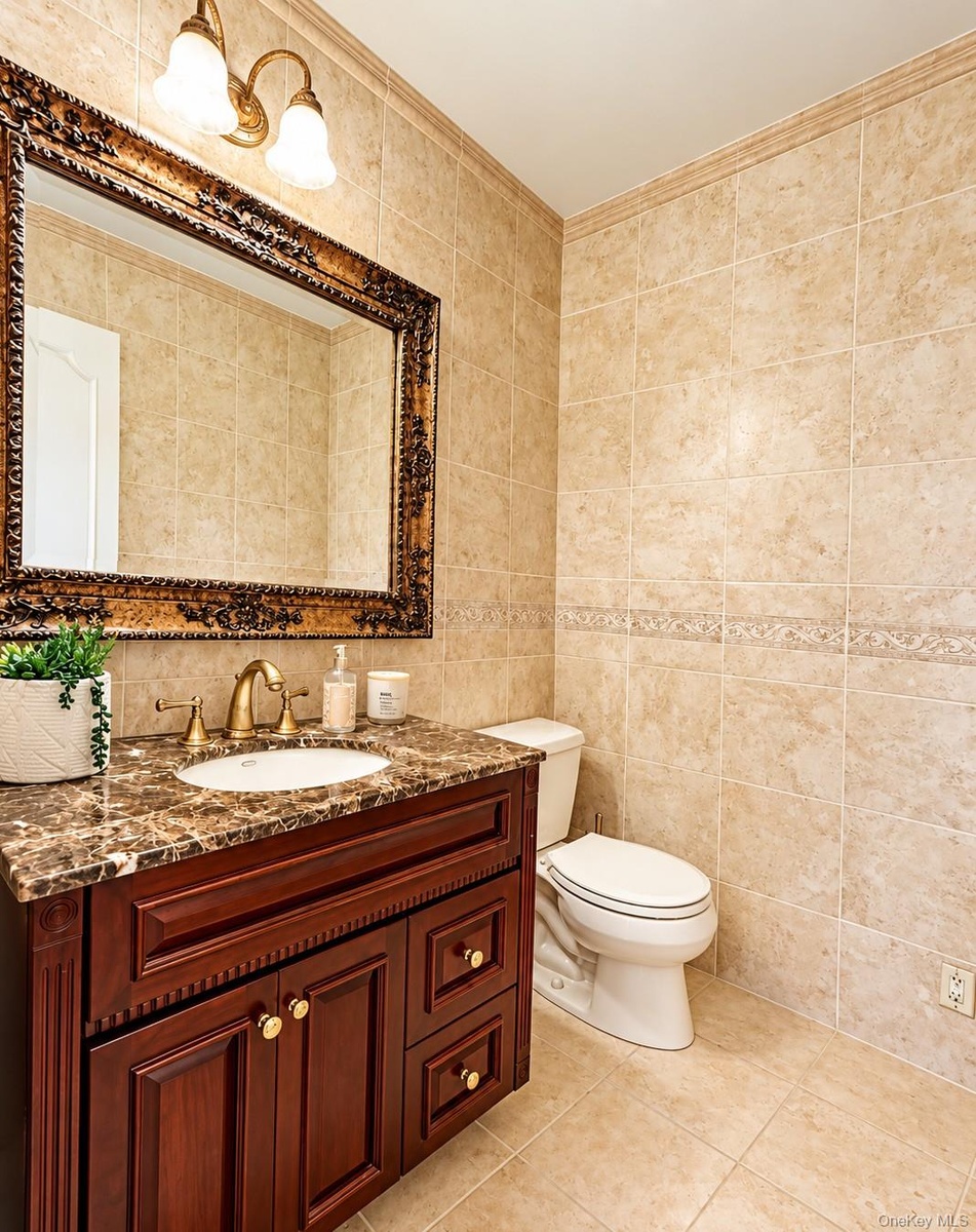 A stylish first-floor powder room features beautiful coordinating floor and wall tile, adding a touch of elegance and sophistication.