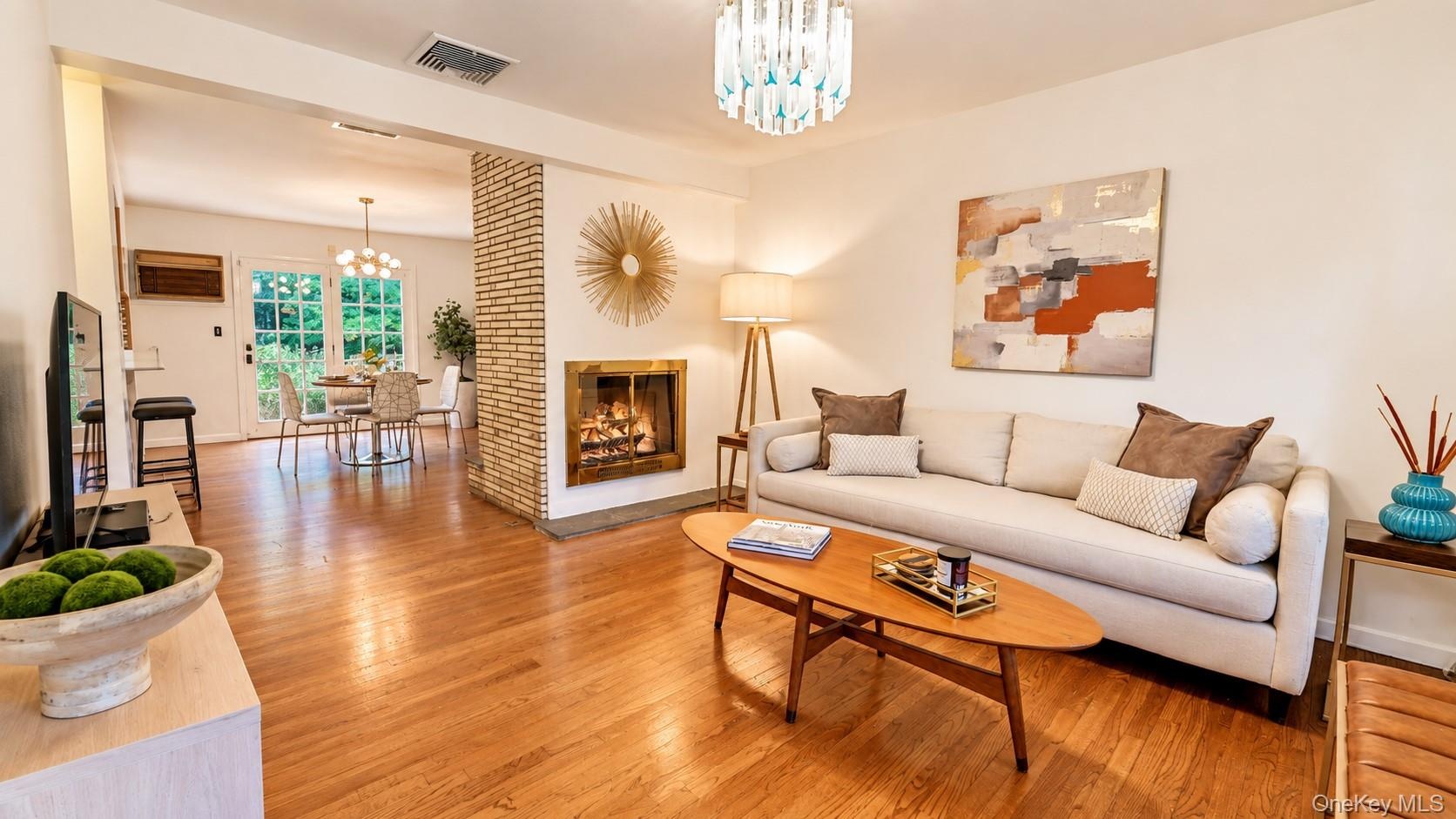 This inviting family room is anchored by a stunning double-sided wood-burning fireplace and an elegant chandelier, creating a warm and sophisticated s