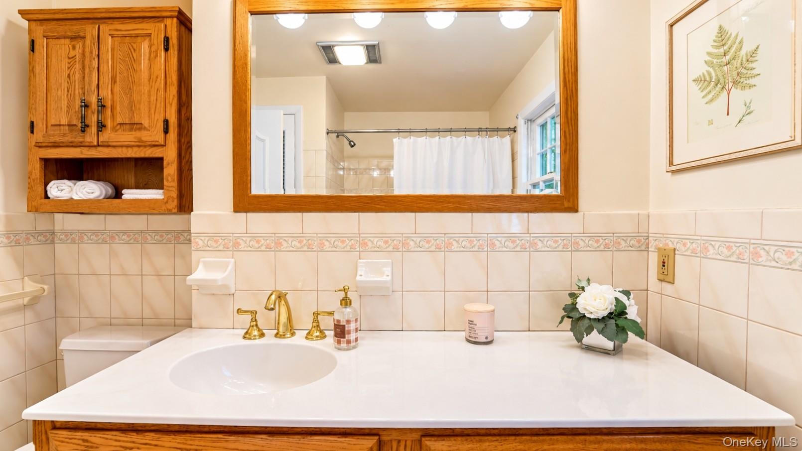 The hallway full bath features a large vanity, stylish accent wall tile, and abundant lighting, creating a bright and beautifully appointed space.