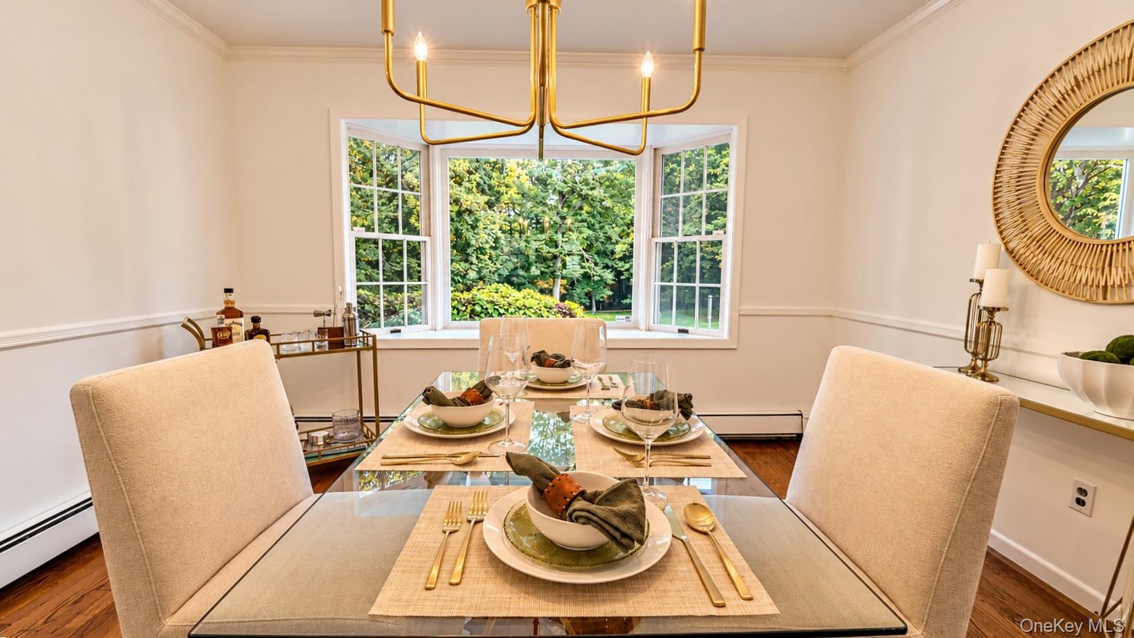 This inviting open-concept dining area features beautiful hardwood flooring and an elegant chandelier, creating a warm and stylish setting for memorab