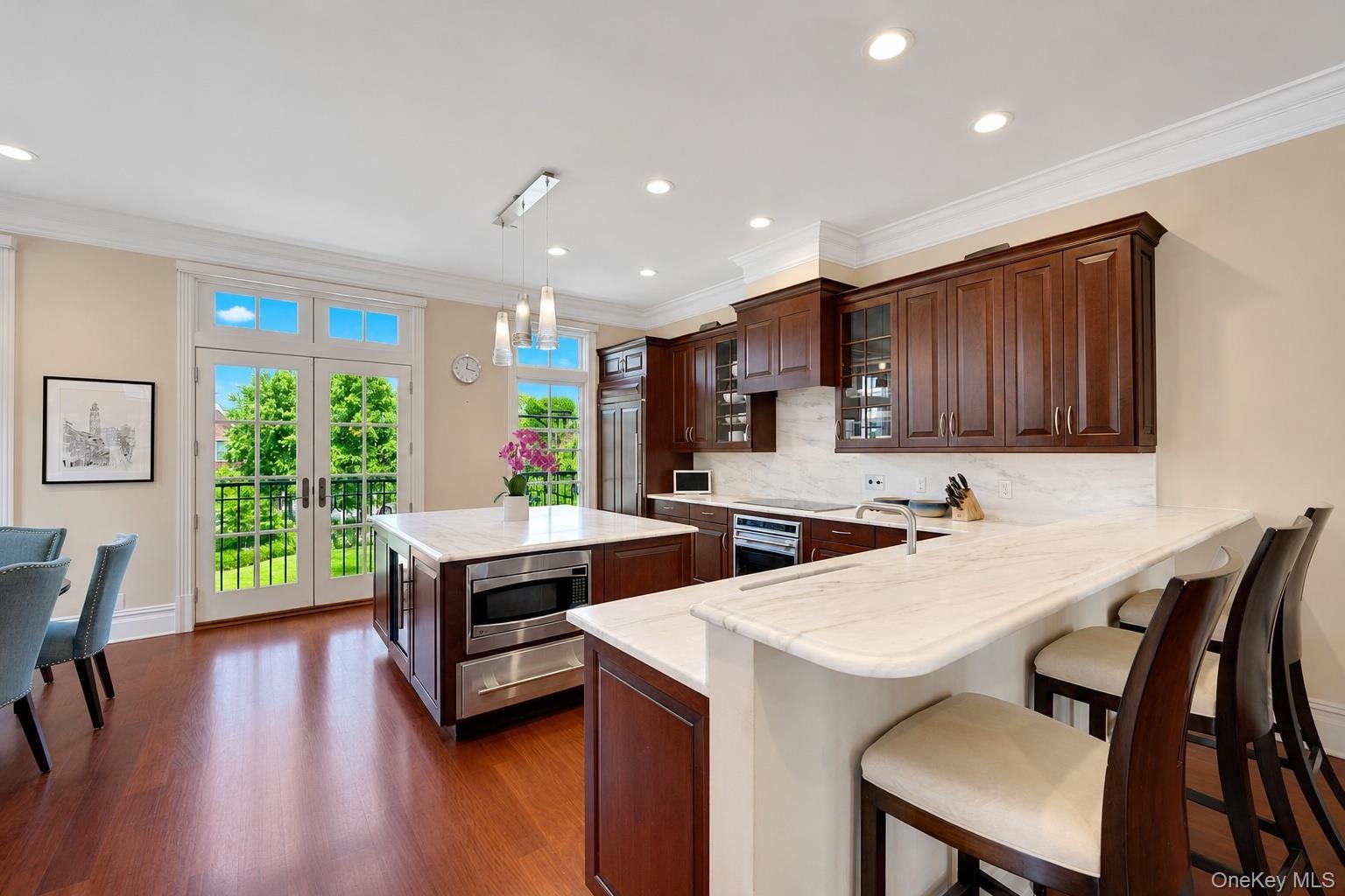 Eat-in chef's kitchen with Wolf induction over&cooktop, SubZero refrigerator, marble counters and island, floor to ceiling windows, and breakfast nook