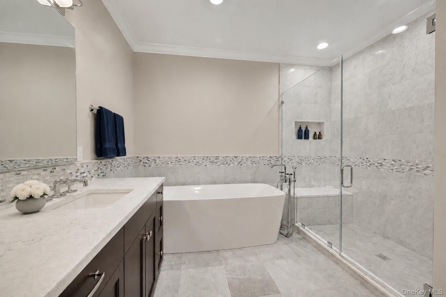 Beautiful marble tile work and spa features in large glass shower