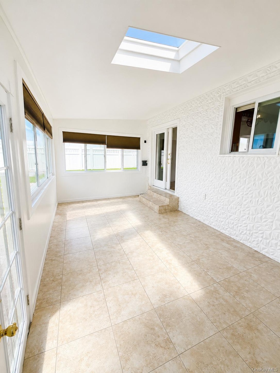 Recessed ceiling skylight, light-toned tile flooring, and multiple windows