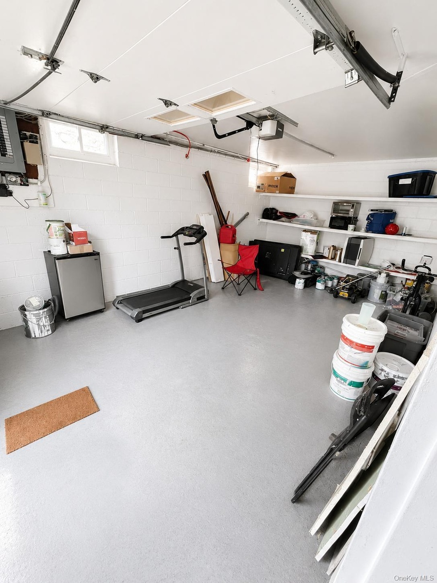Garage with finished light gray flooring, white walls, and built-in shelving