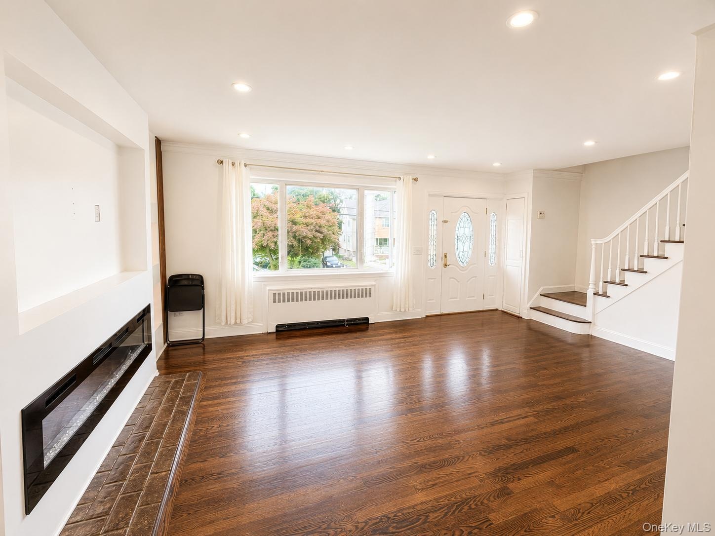 Wood-finish flooring, recessed lighting, and a built-in linear fireplace with a tiled hearth