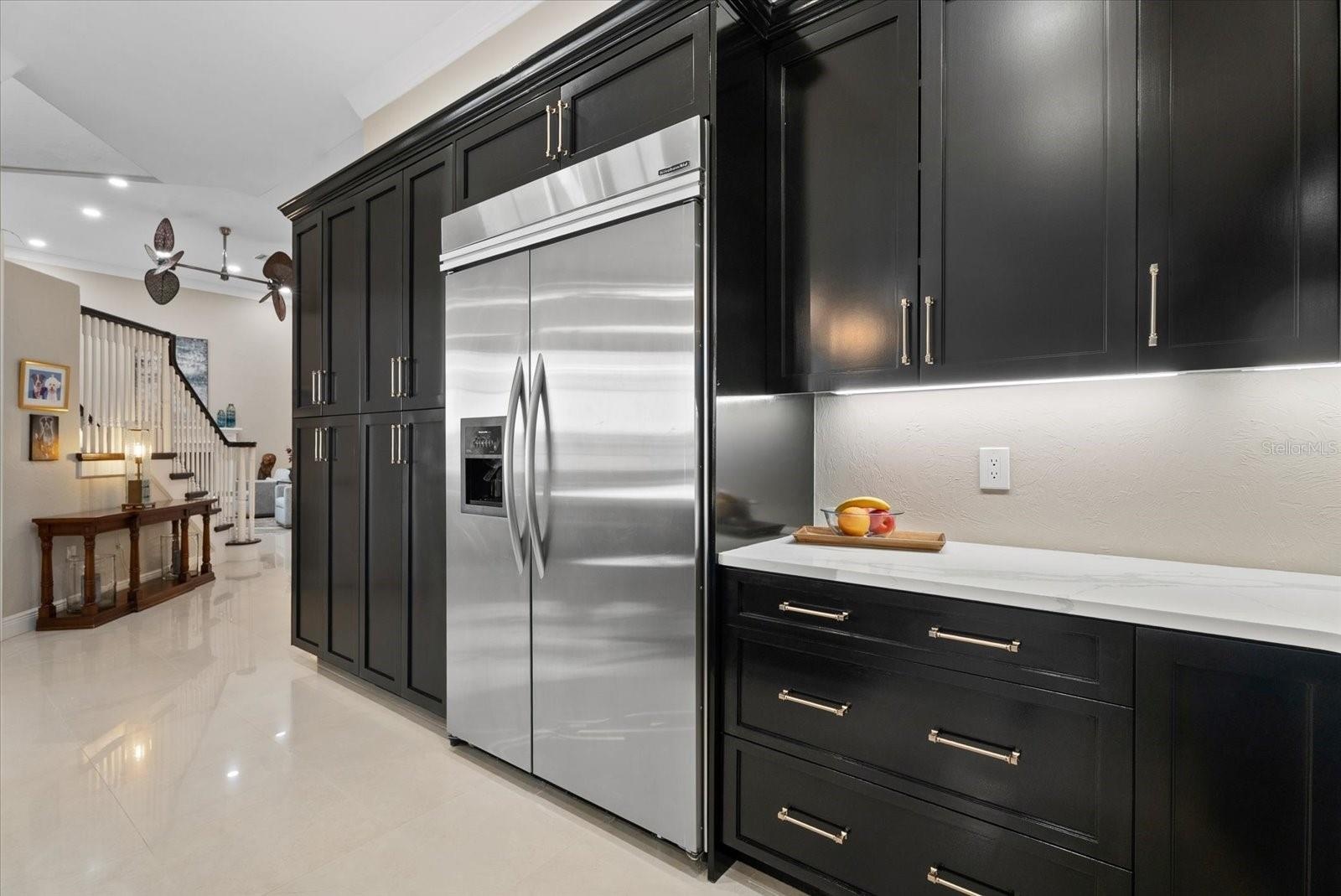 High end stainless steel appliances and a bank of custom cabinets are shown.  There is also a walk-in pantry and two other closets accessible to the k