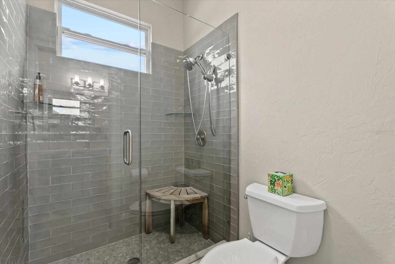 The toilet and shower area are closed off from the shared sink area of the Jack and Jill bathroom upstairs