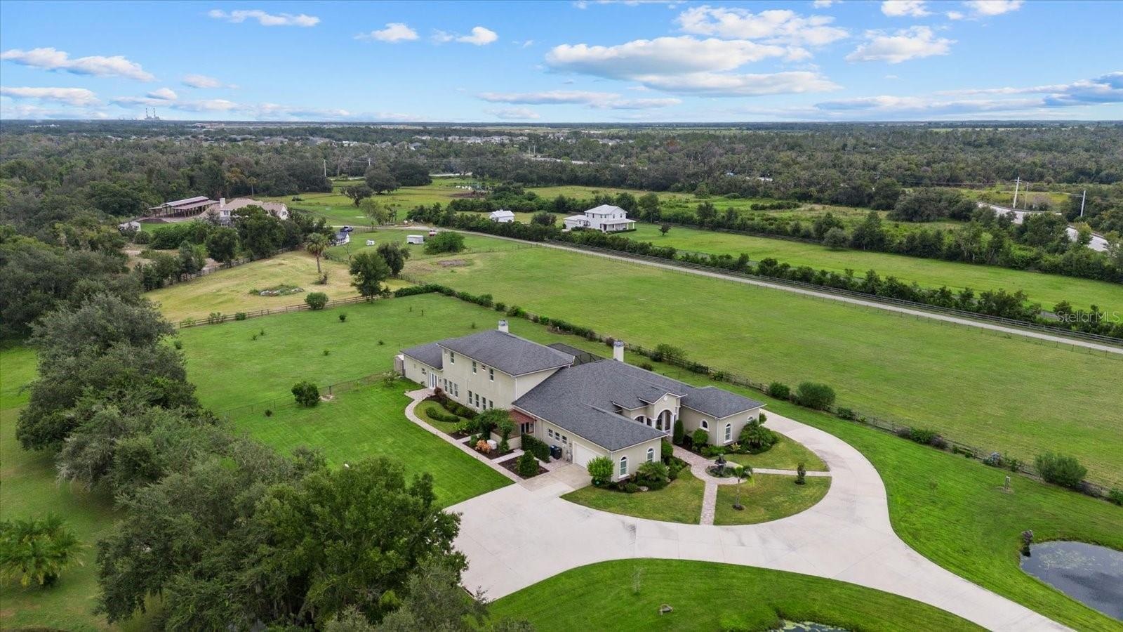 This drone shot shows the main house, front pasture behind the home and a triangle shaped pasture beyond it.