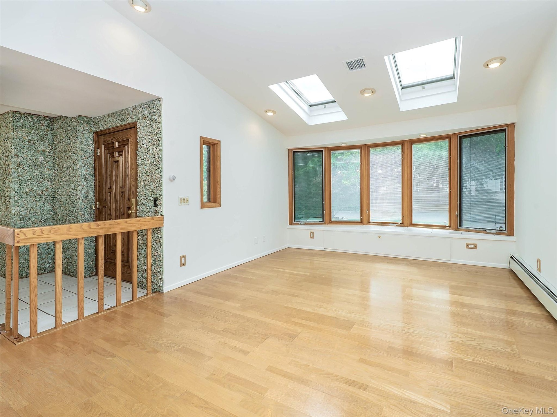 Extended living room with skylights and front bay window with storage.