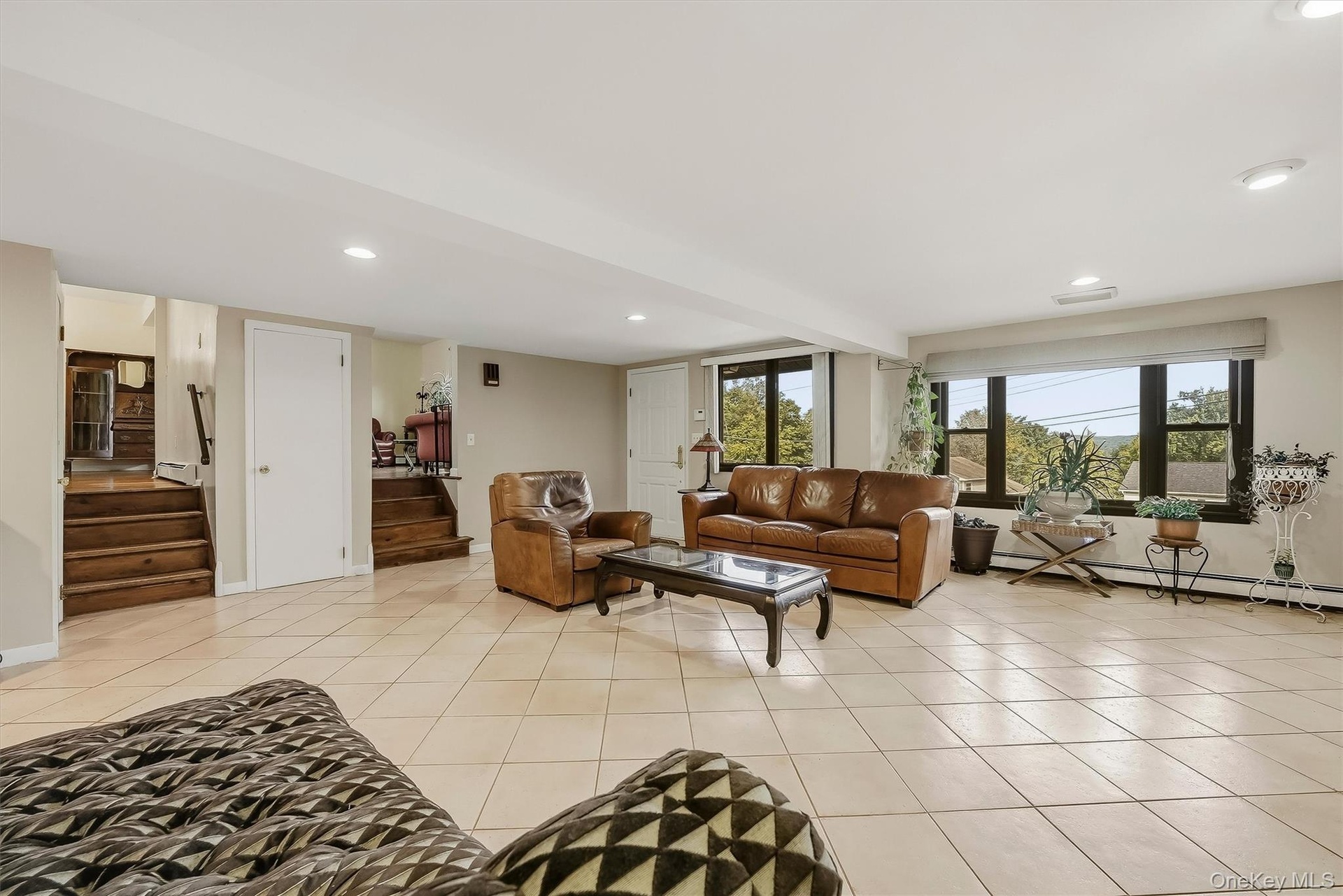Spacious 1st level recreation room with large windows, recessed lighting, and light-toned tile flooring