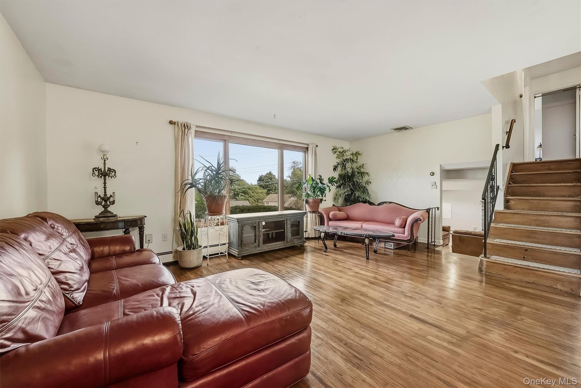 Second level living room featuring wood flooring, and a large  window with a view. Steps lead up to bedroom level or down to recreation room.