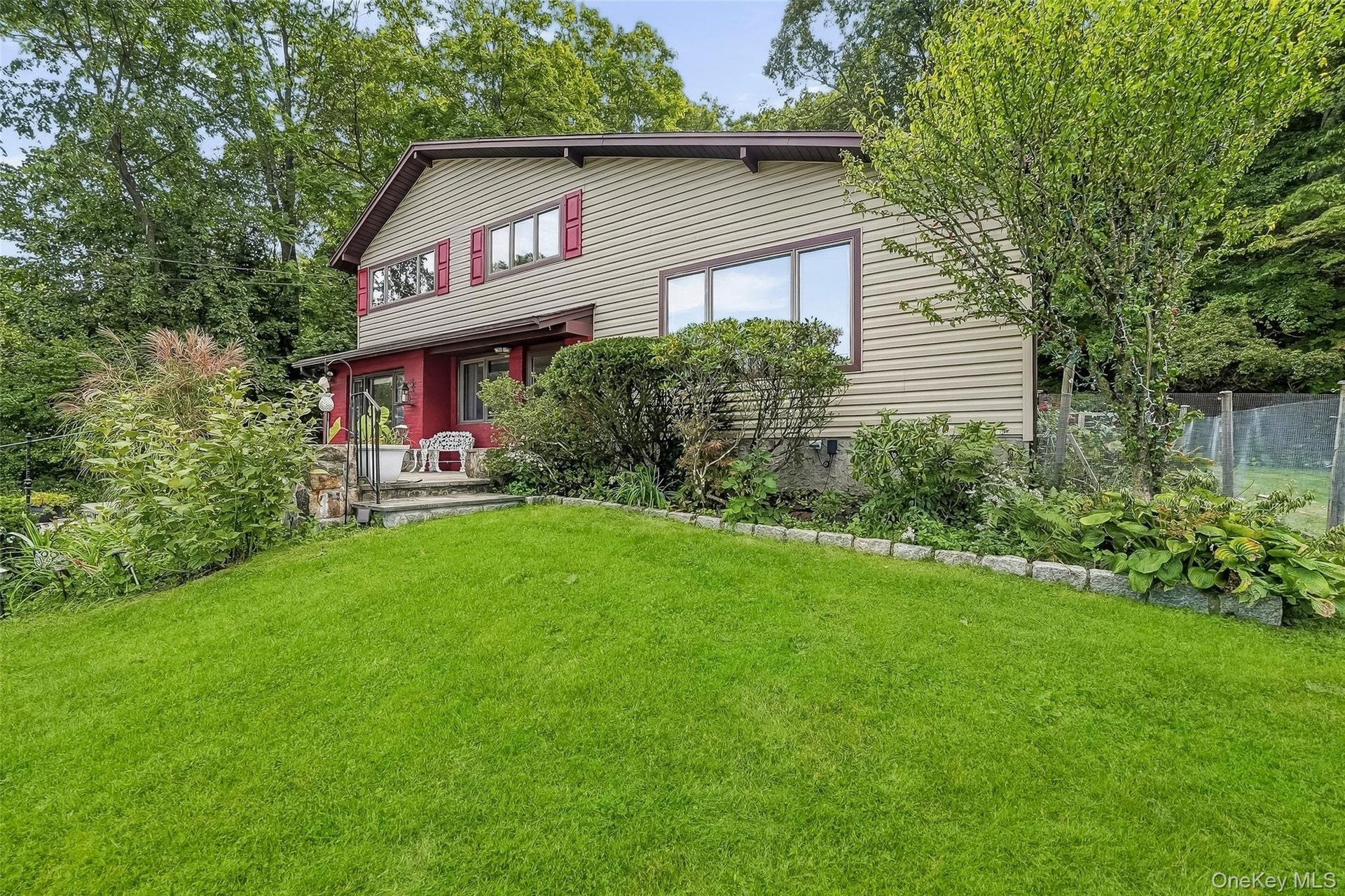 Split-level residence with red shutters, and a covered entry.