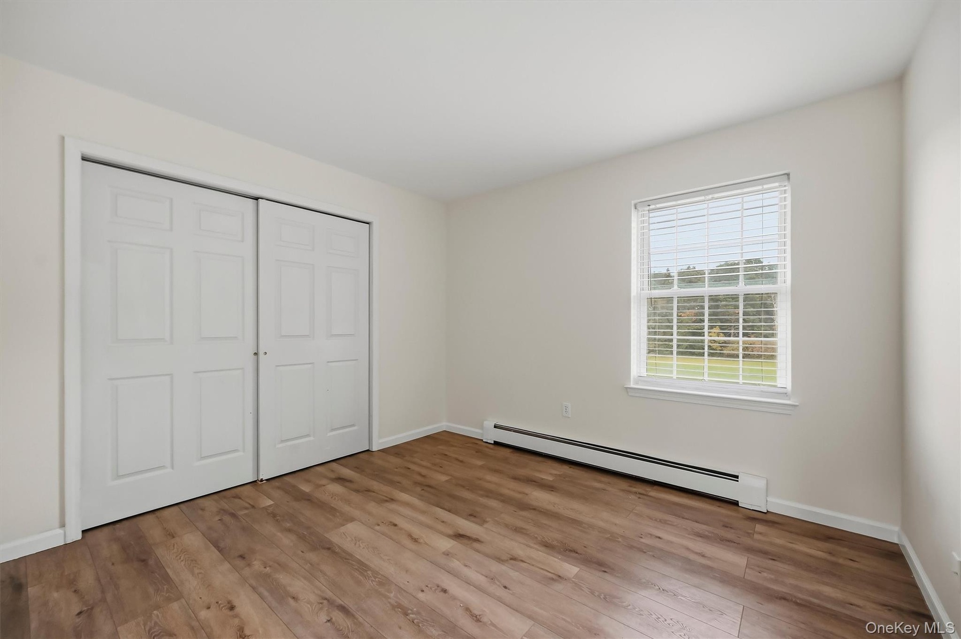 Third bedroom with warm flooring and a full wall of closet space.