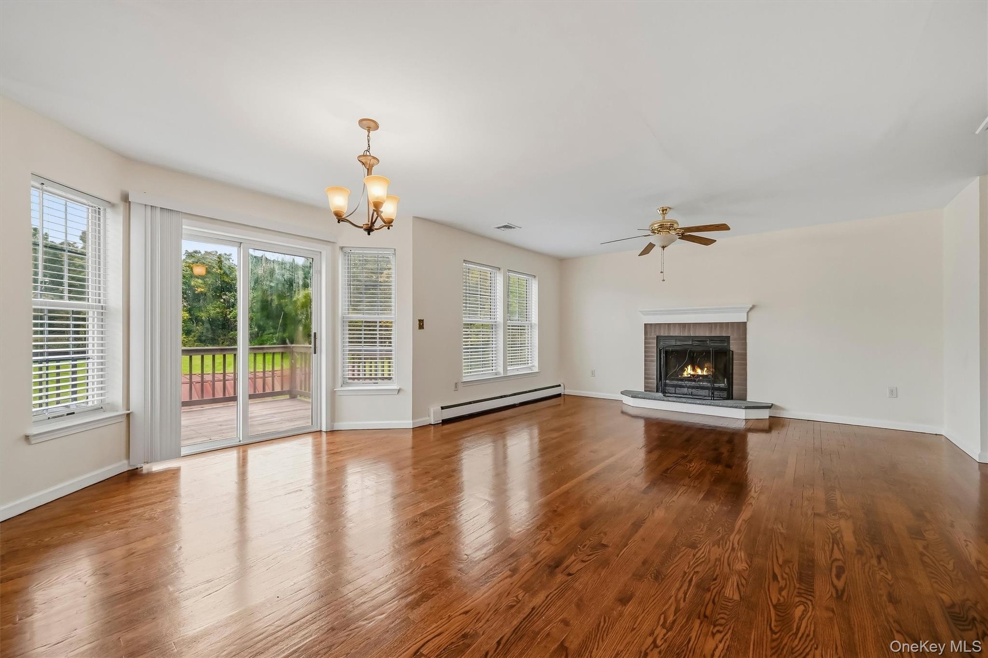 A wall of windows, rich hardwood floors, and a fireplace make this living space one of the home’s standout rooms.