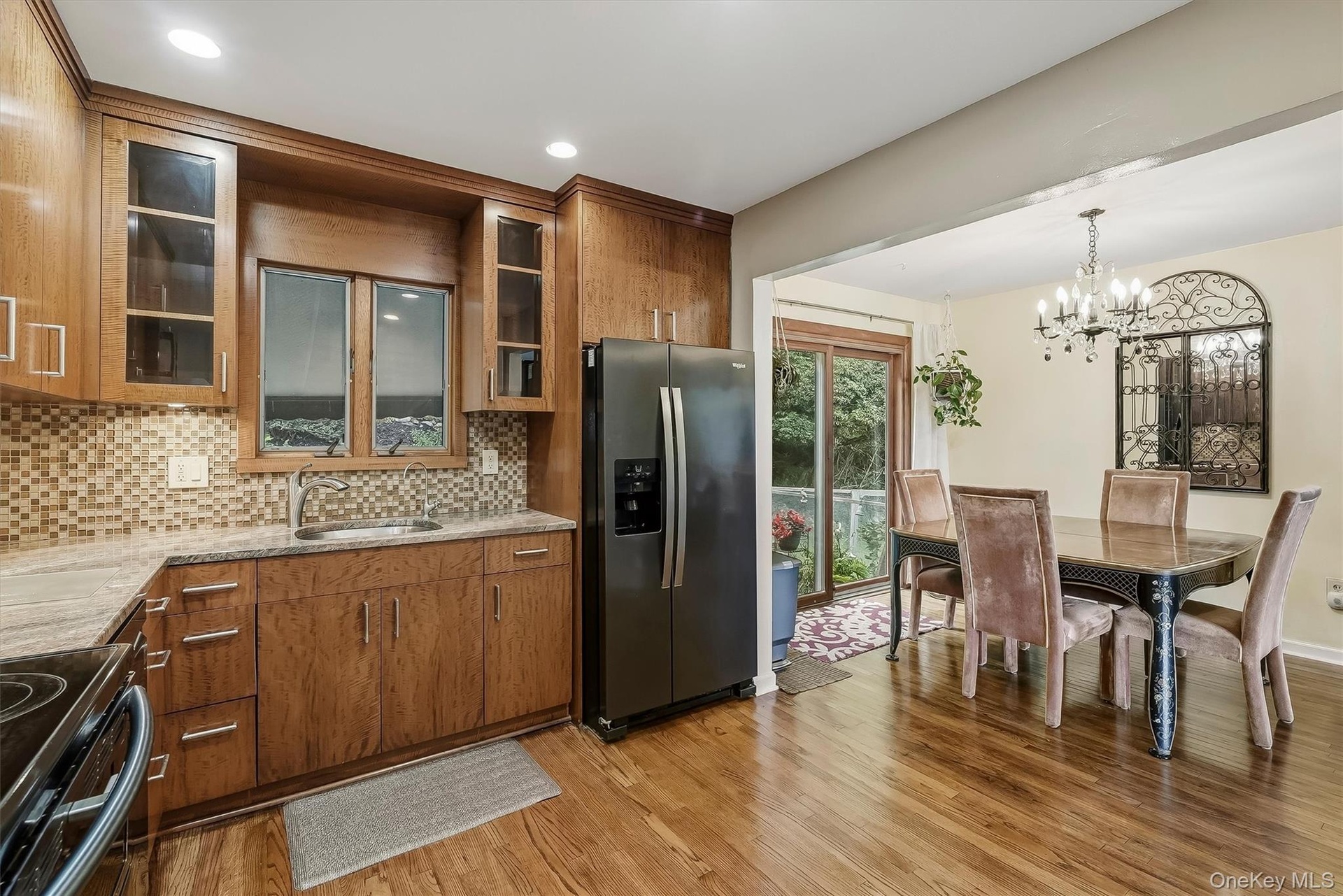 Kitchen featuring wood cabinetry and flooring with access to dining area and backyard.
