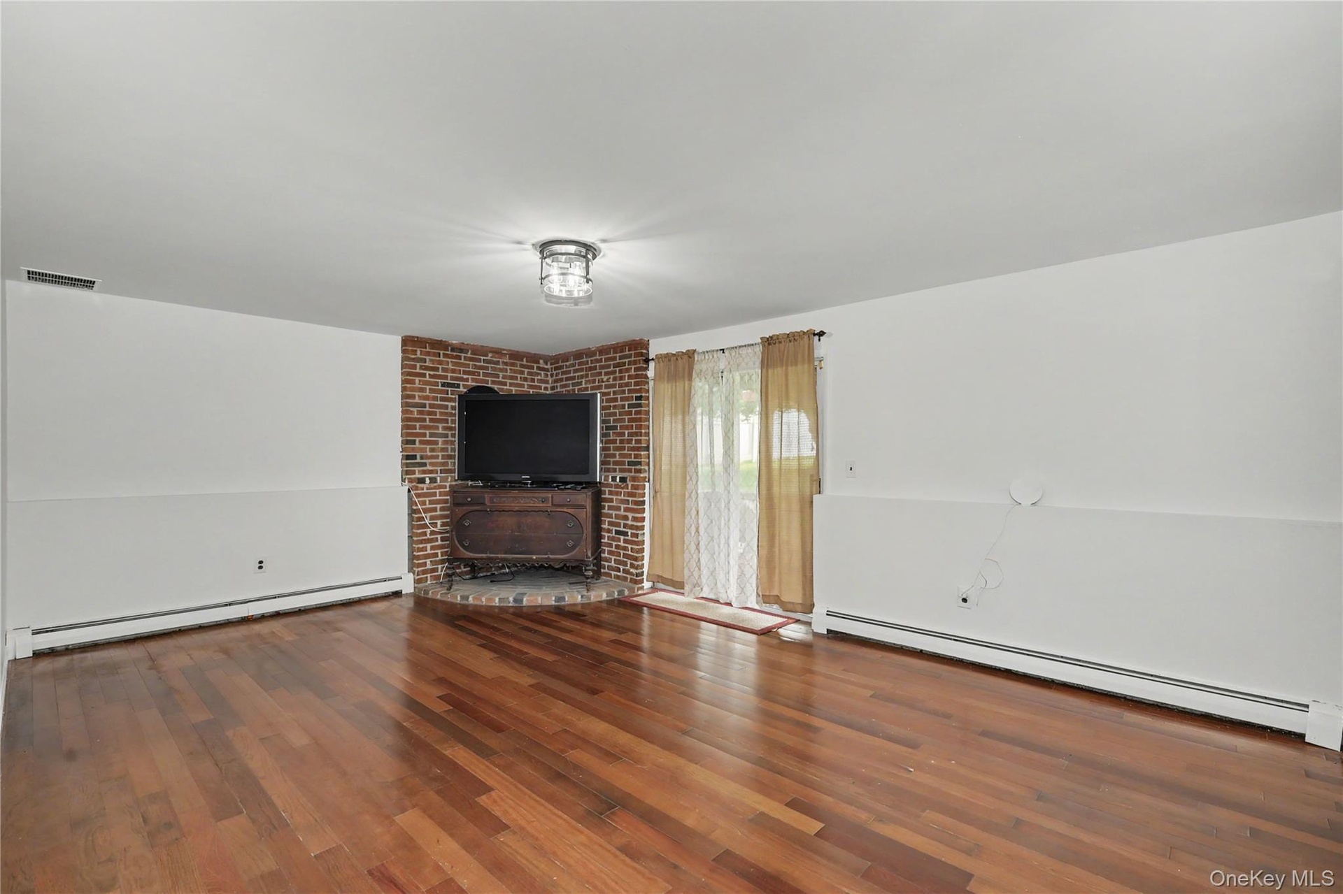 Huge family room with bricked platform for woodburning stove and glass sliders to backyard