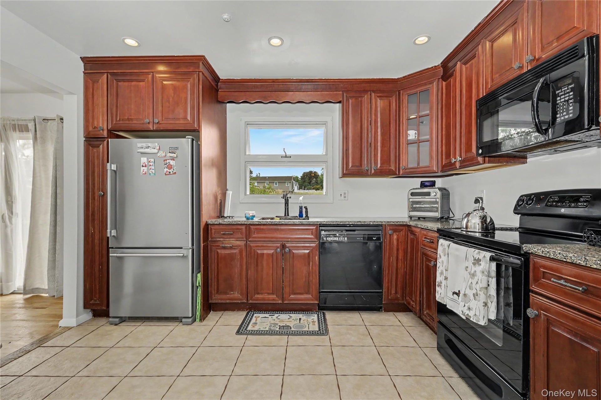 Well equipped and ample kitchen featuring wood cabinetry, recessed lighting, tile flooring and pantry