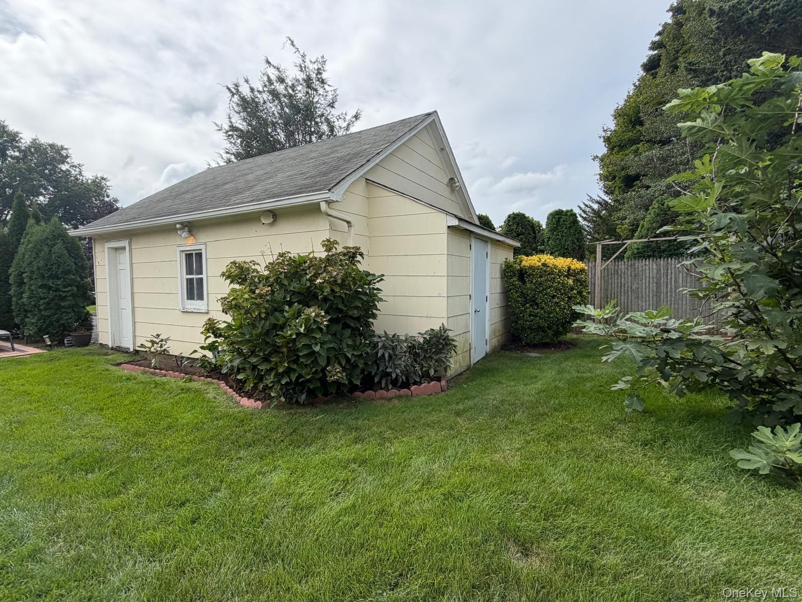 Detached  2 car garage with vinyl siding, a pitched roof, a single window, Door on the side.