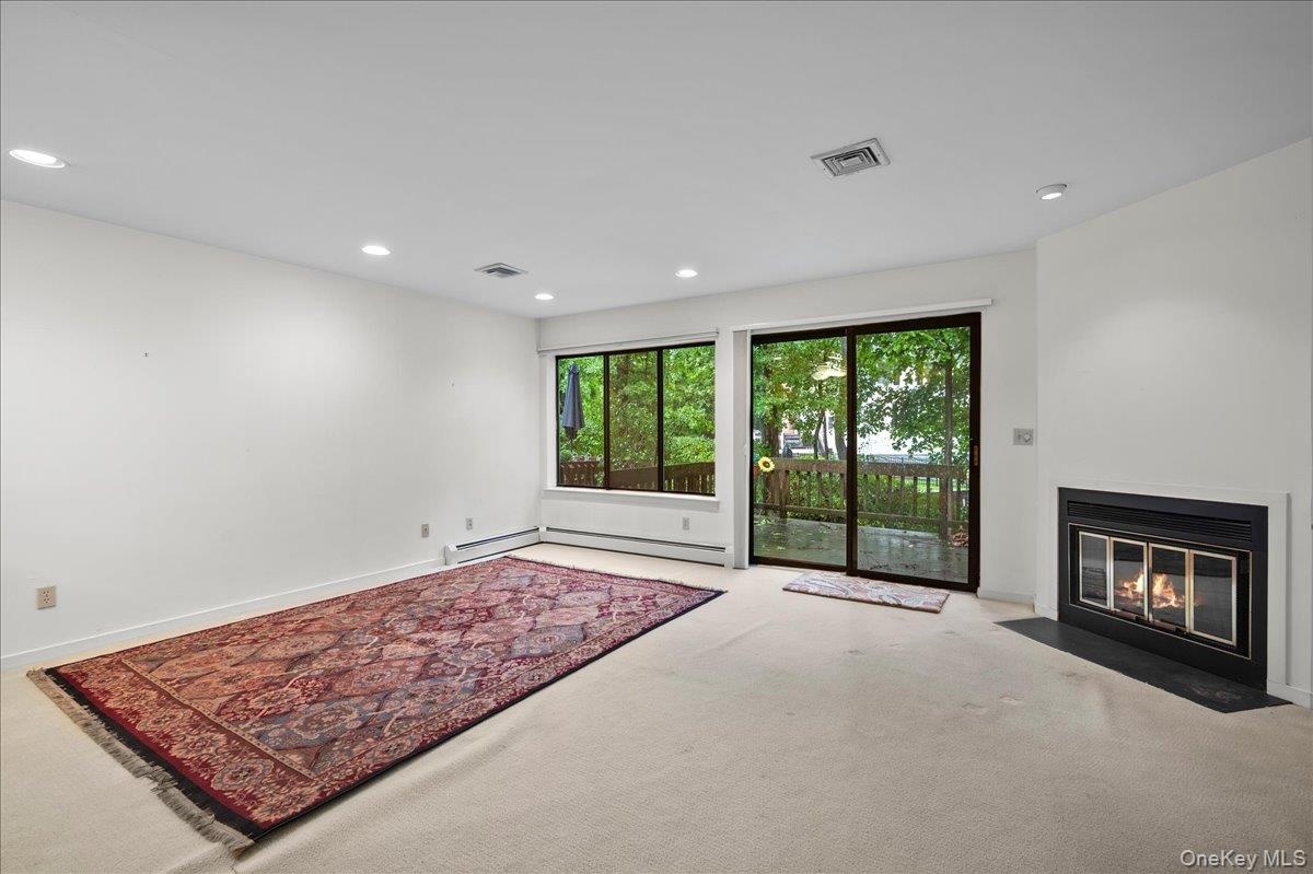 View of the living room looking out to the wood-burning fireplace and glass sliders to the patio