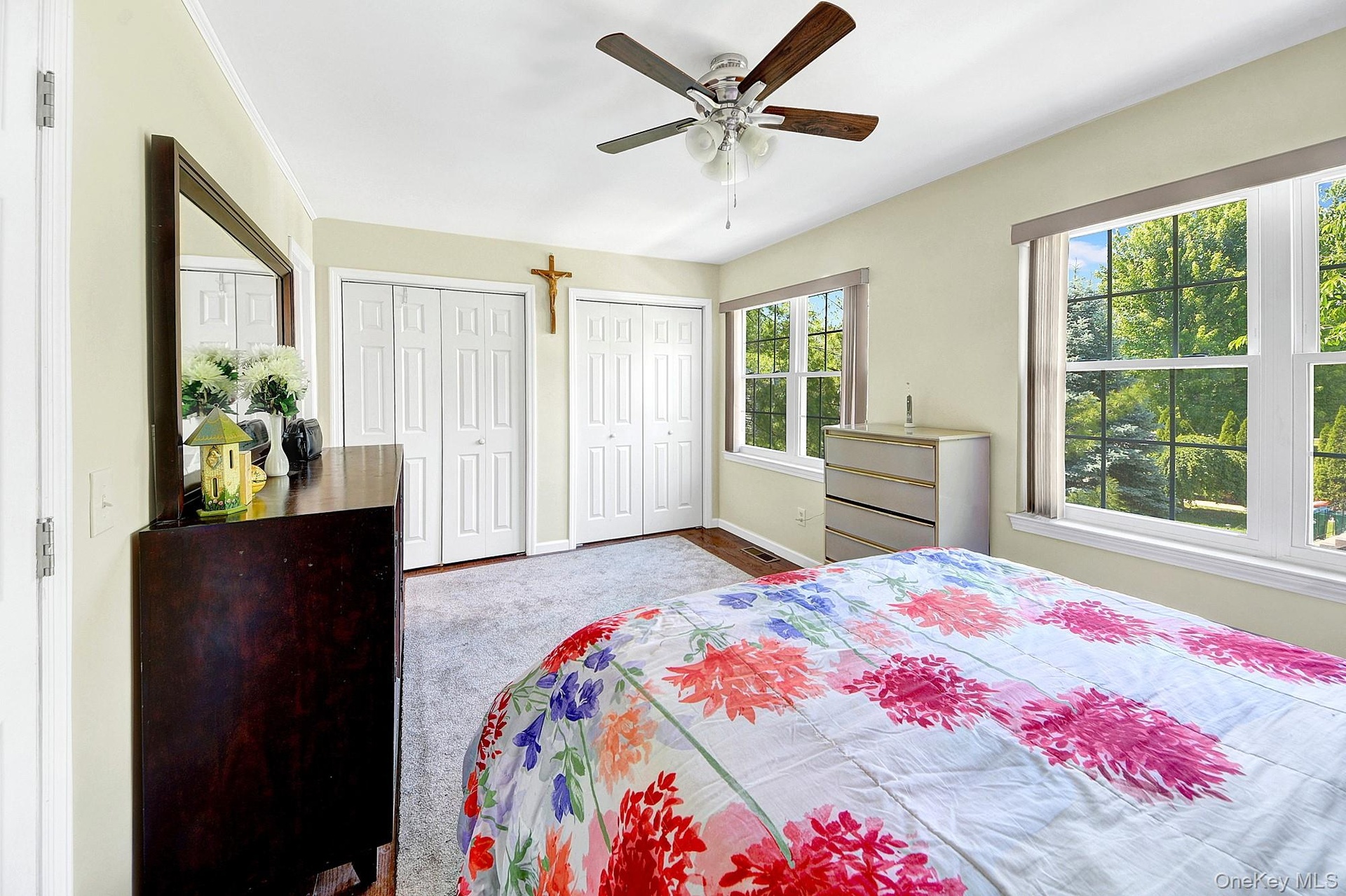 Primary bedroom with large windows, large closets, hardwood floors and an en-suite bathroom