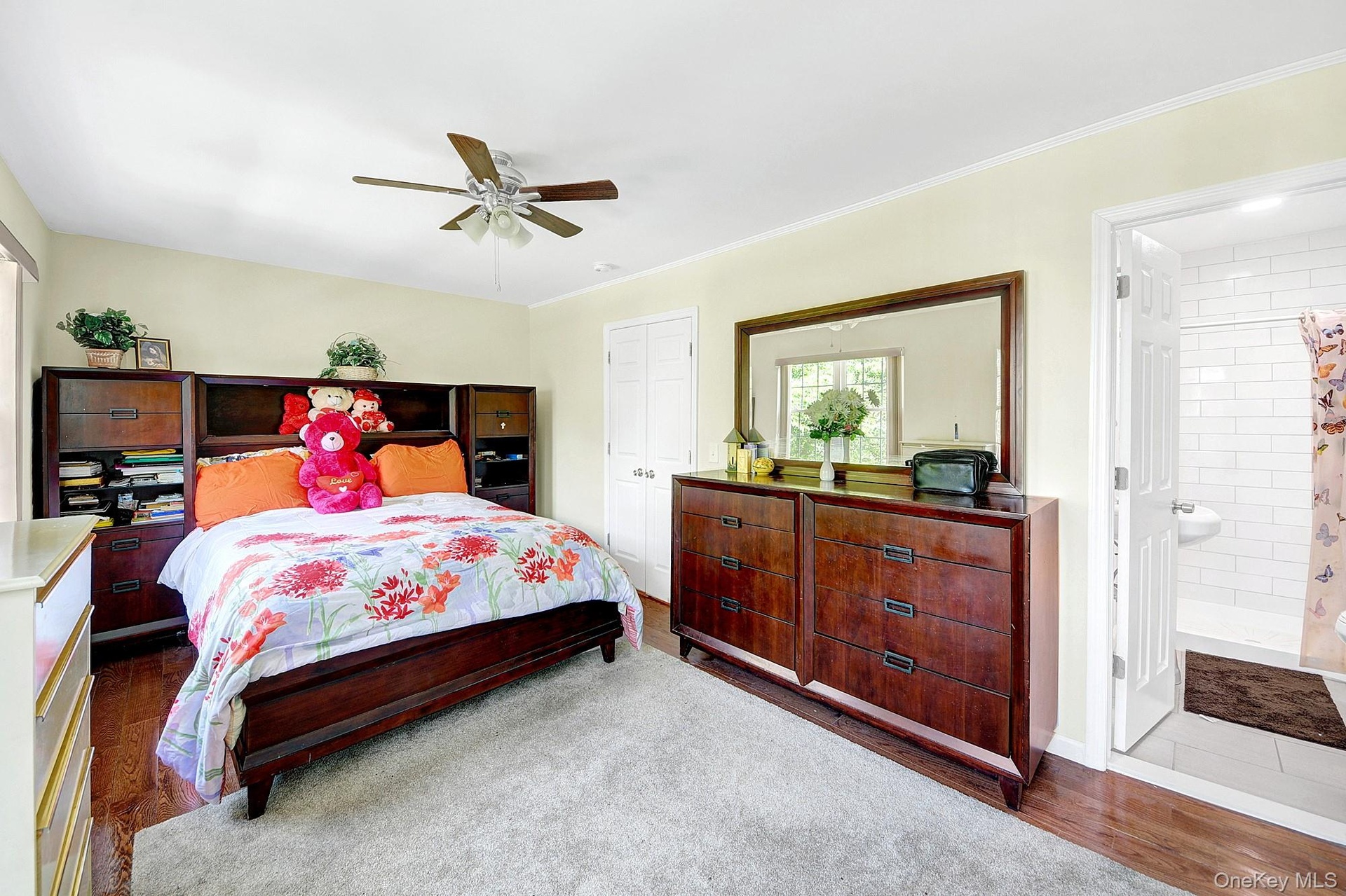 Primary bedroom with large windows, large closets, hardwood floors and an en-suite bathroom