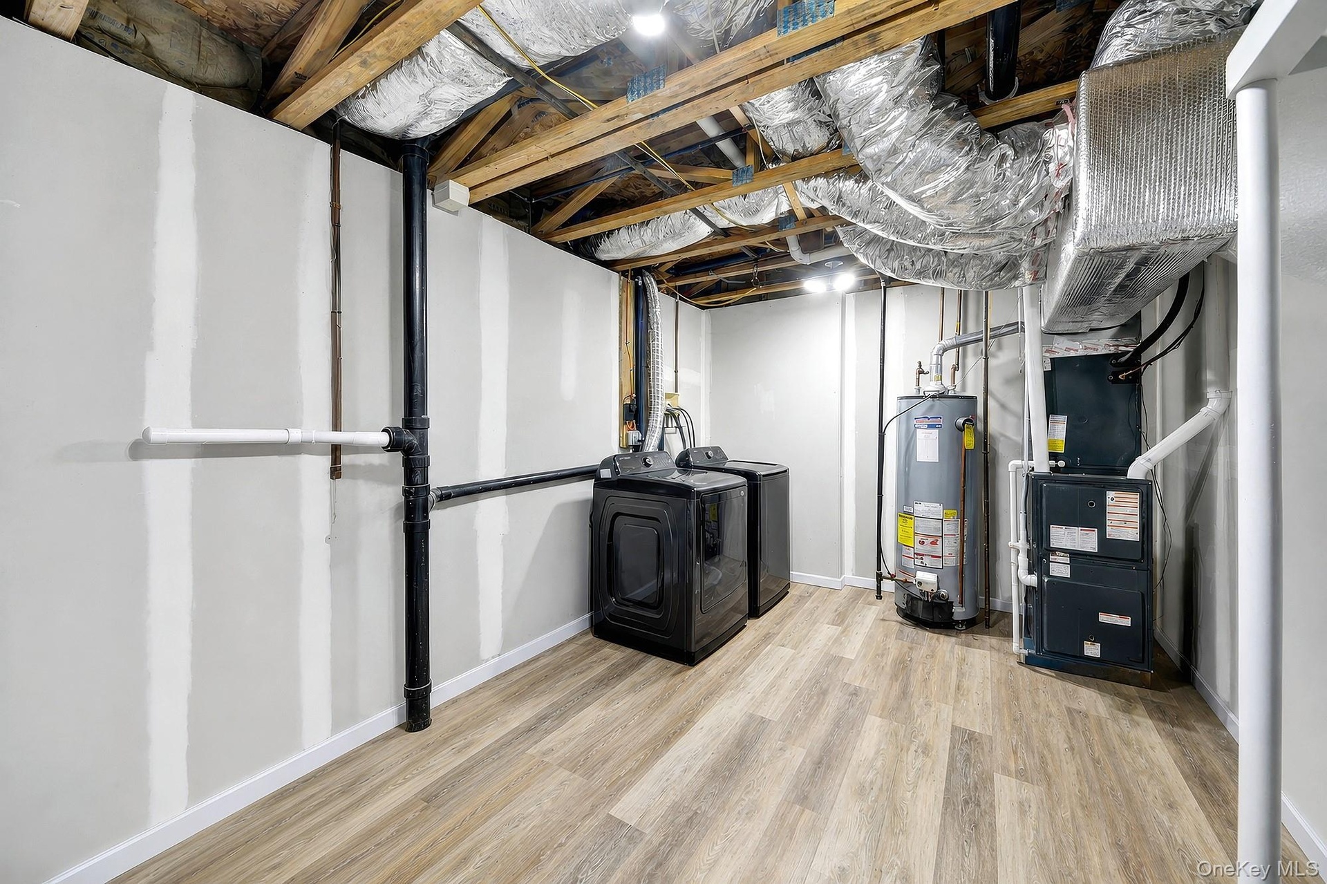 Utility room with forced air heating and cooling system and washer/dryer units