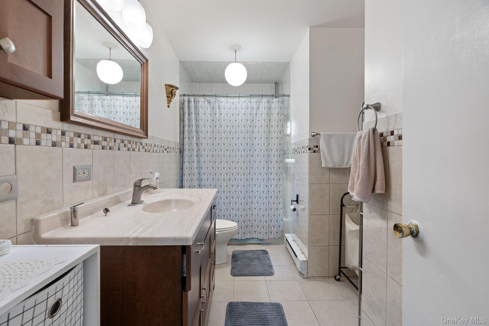 Bathroom with tile walls, vanity, tile patterned floors, toilet, and tiled shower