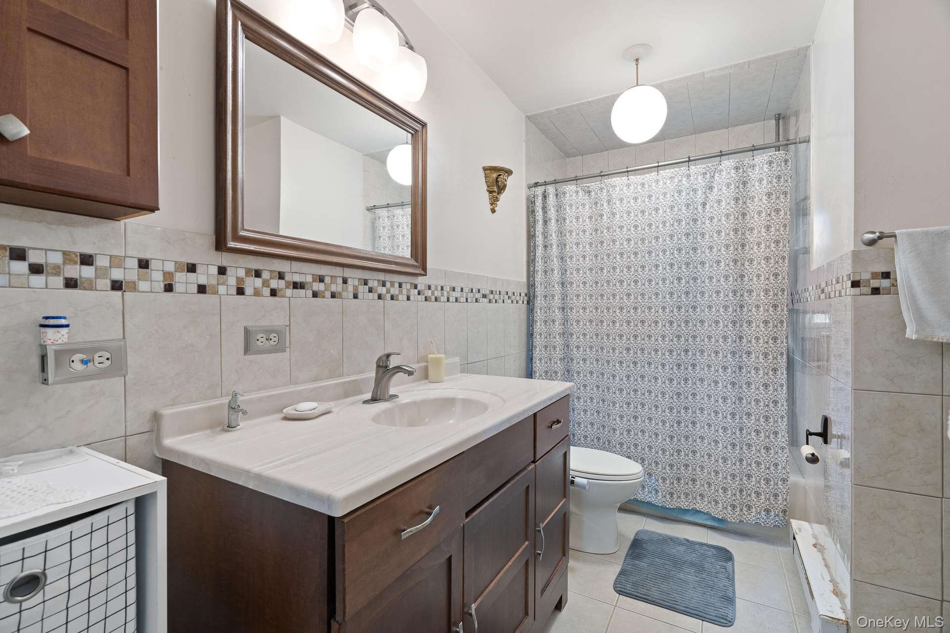Bathroom with tile walls, vanity, tile patterned flooring, toilet, and curtained shower