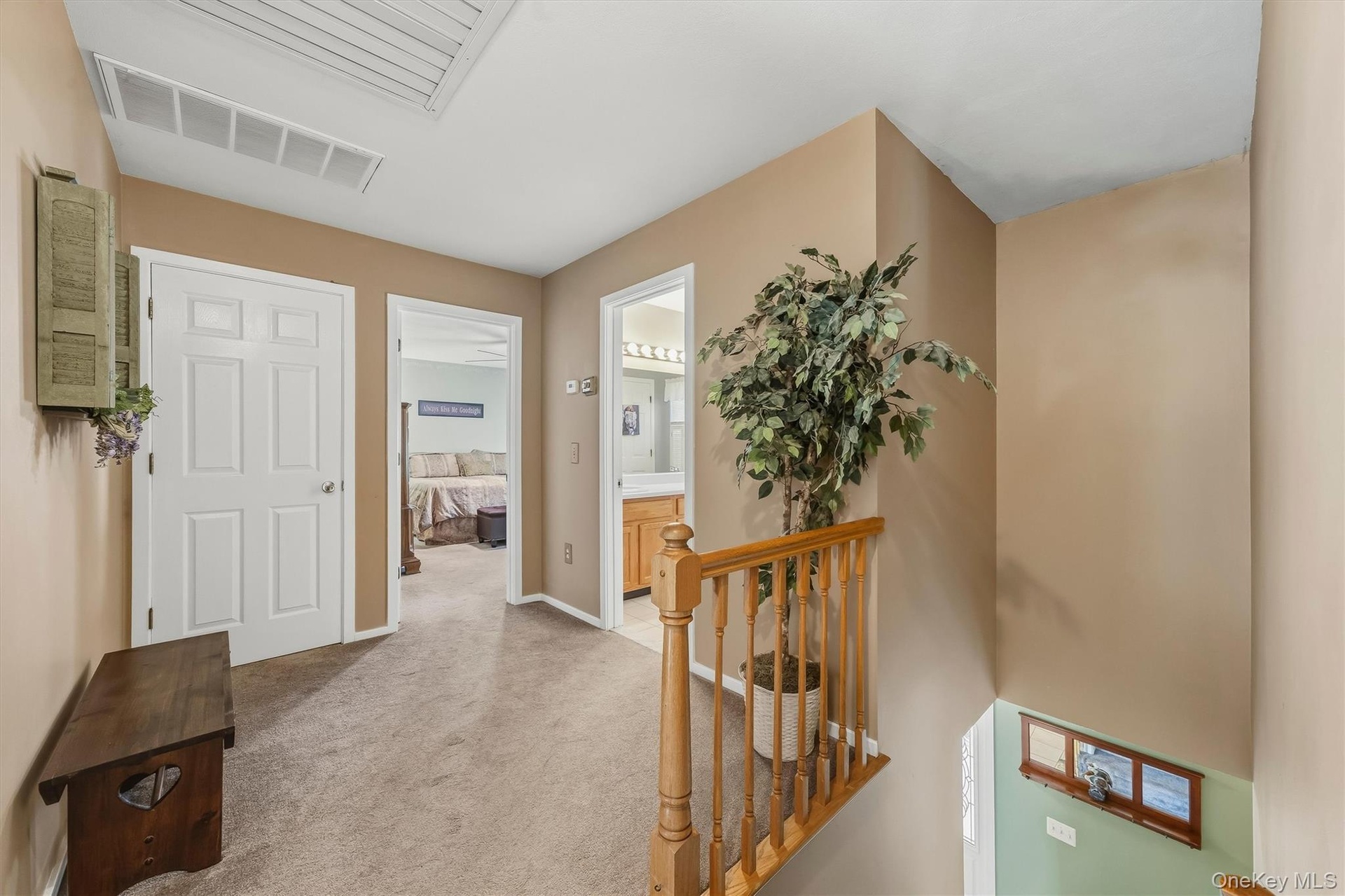 Carpeted hallway with painted walls, white doors, and a wood railing