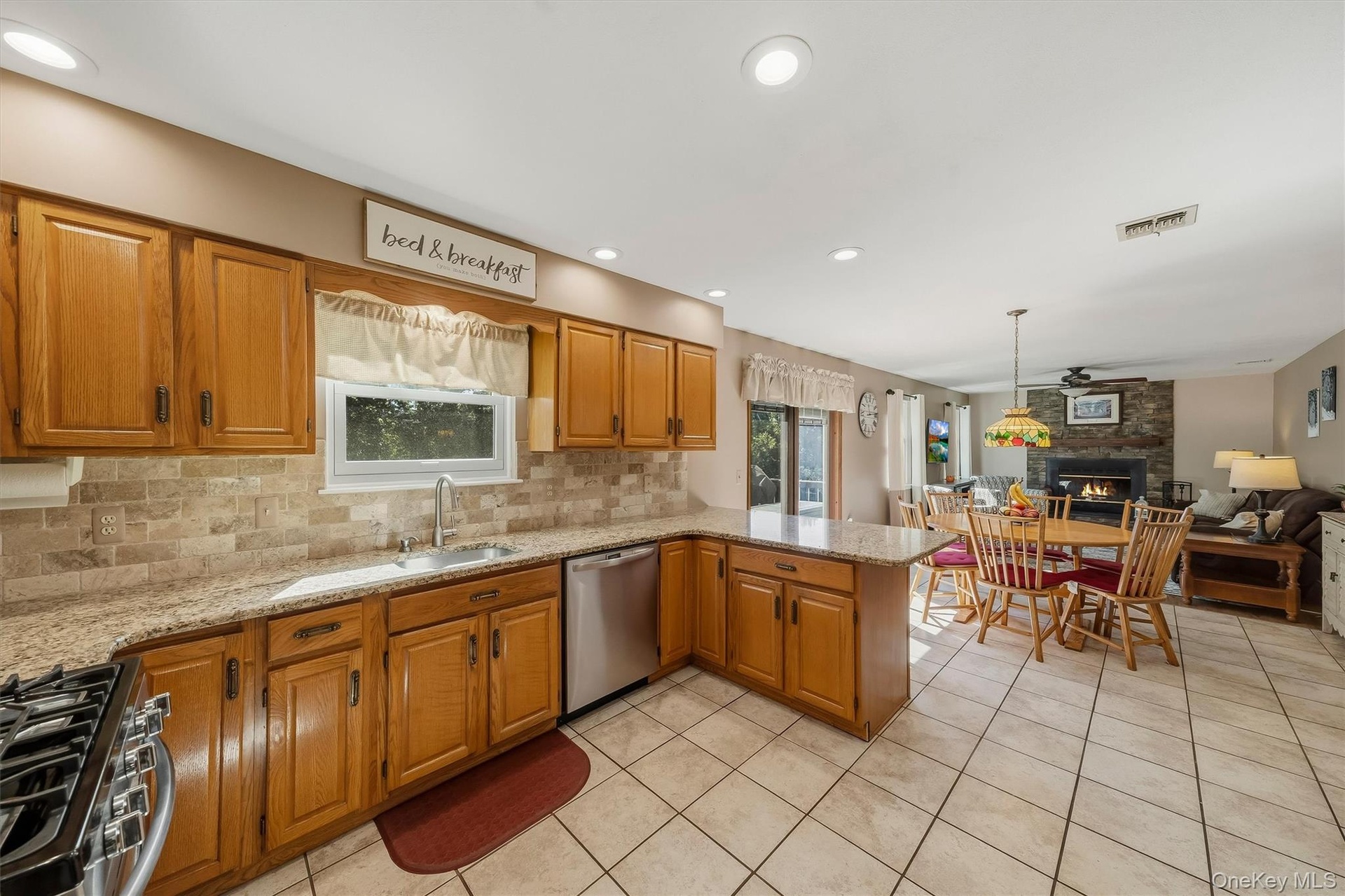 Kitchen featuring wood cabinetry, light-toned stone countertops, and a tiled backsplash